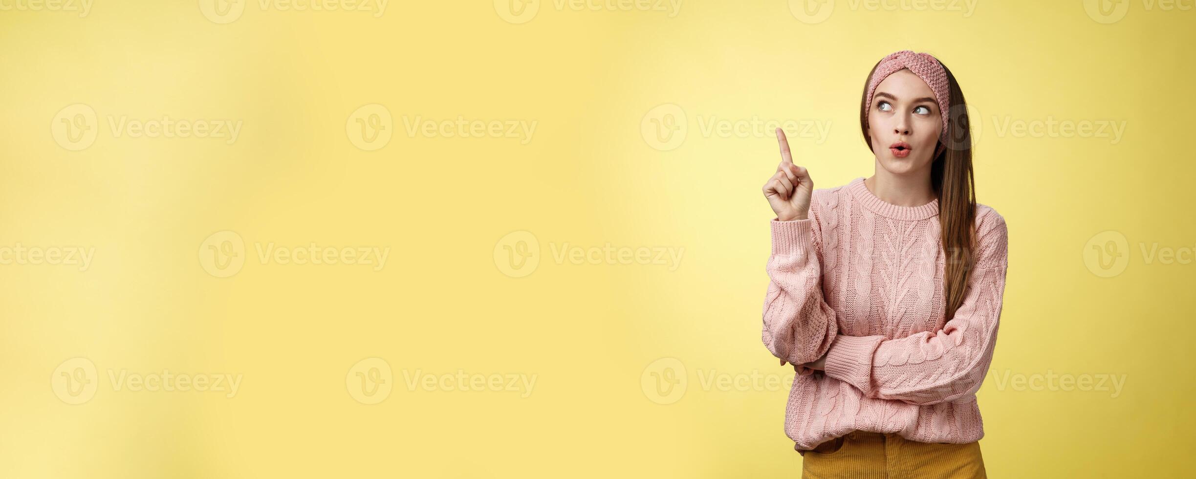 Lightbulb, I have idea. Amused and enthusiastic creative young female project manager raising index finger, showing eureka gesture folding lips intrigued looking up suggesting plan came to mind photo