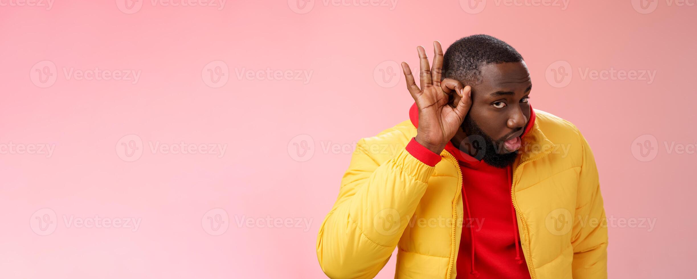 Curious funny charismatic black bearded guy bending forward hold hands ear eavesdropping wanna overhear girlfriend conversation behind door standing curious gossiping pink background photo