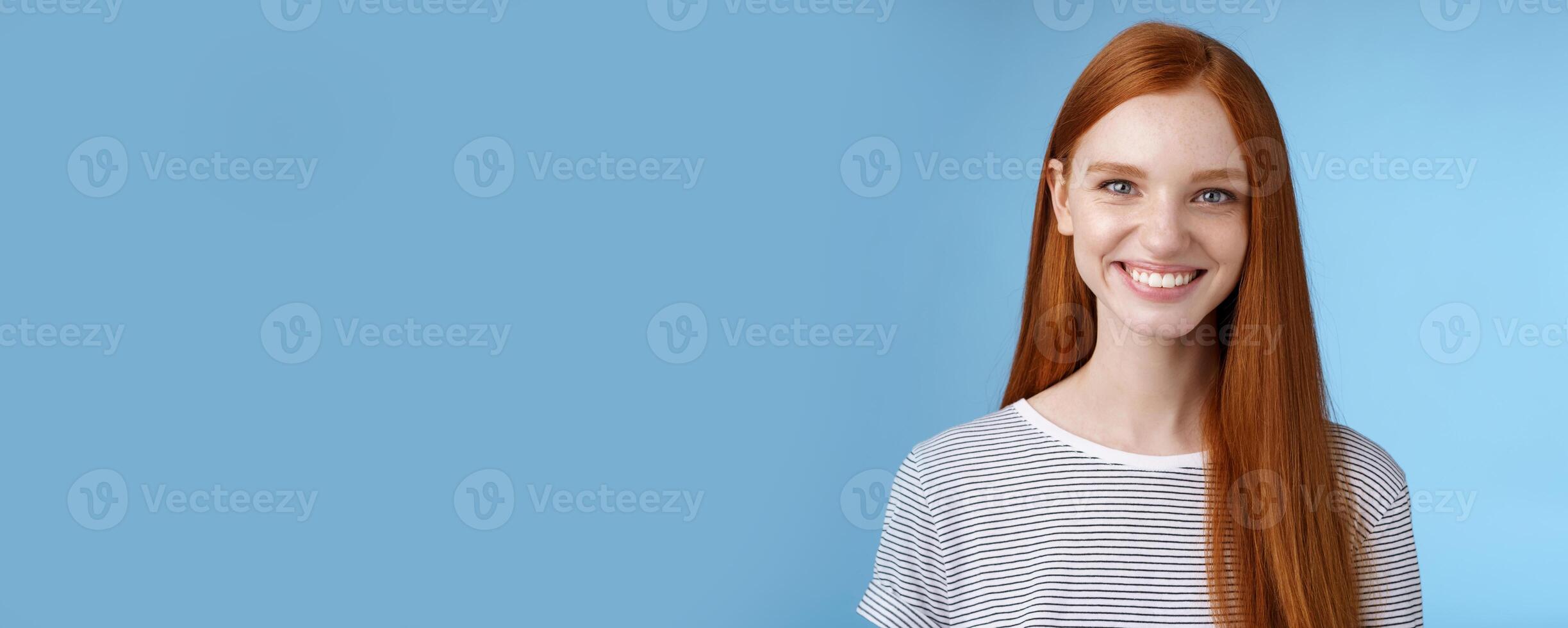 Pleasant reliable sincere good-looking redhead female freelancer college student make confident professional impression smiling broadly assertive helpful standing blue background self-assured photo