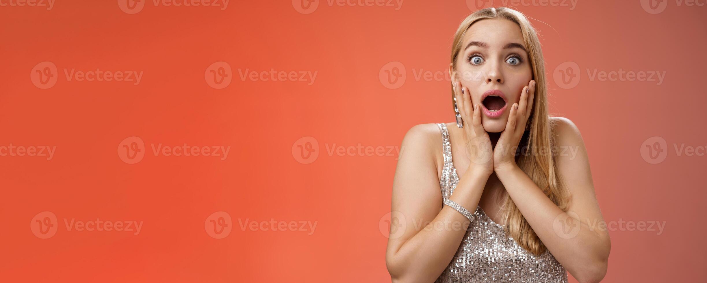 Shocked speechless concerned young stunned woman gasping screaming worried drop jaw touch cheeks widen eyes surprised nervously staring camera troubled afraid, standing red background photo