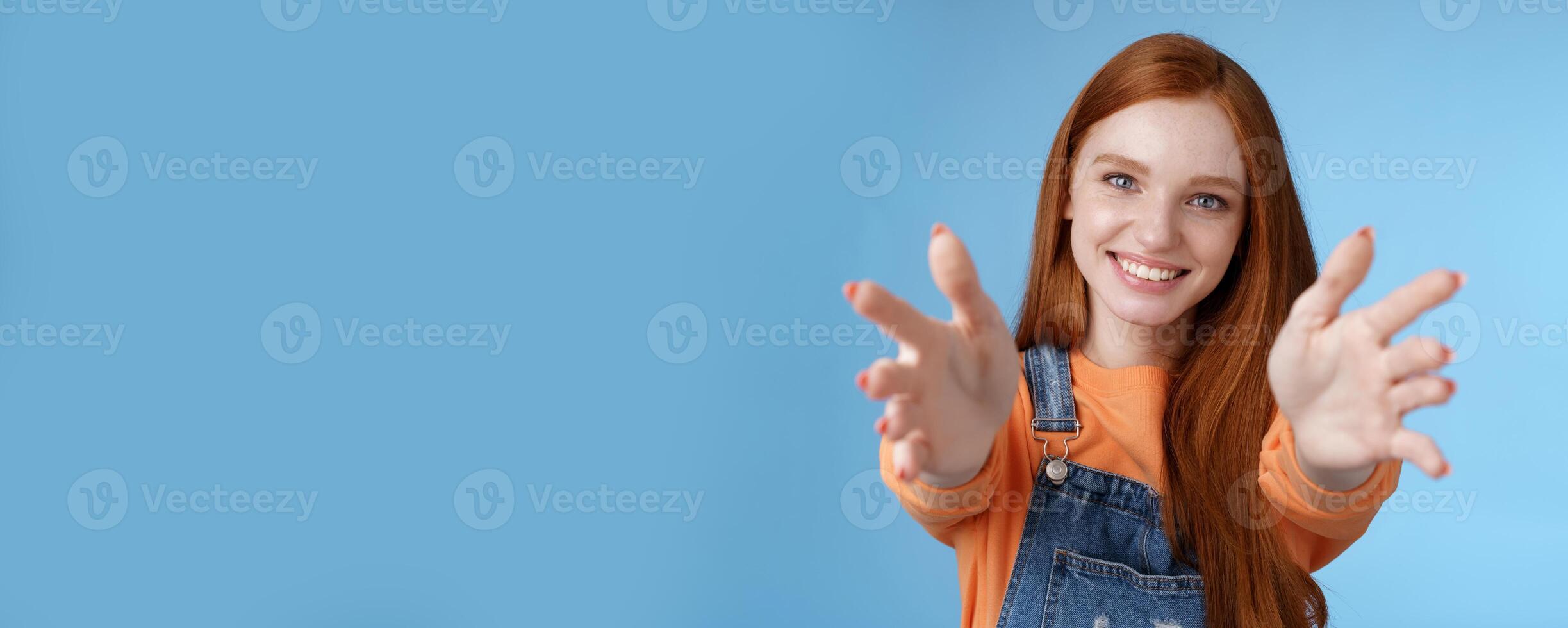 Come into arms. Charming sincere happy kind redhead girl baby sitting stretch hands camera wanna hold catch smiling friendly asking pass object, standing blue background reach friend give cuddles photo