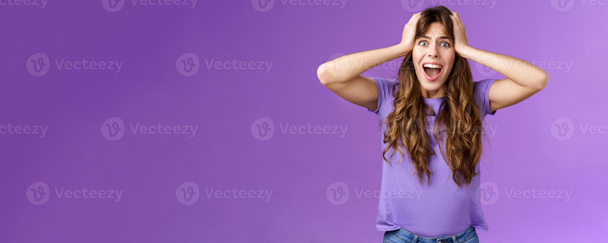 Shocked upset disappointed curly girl shouting sorrow face troublesome shocking situation grab head scream panic outraged pissed and angry, standing distressed purple background photo