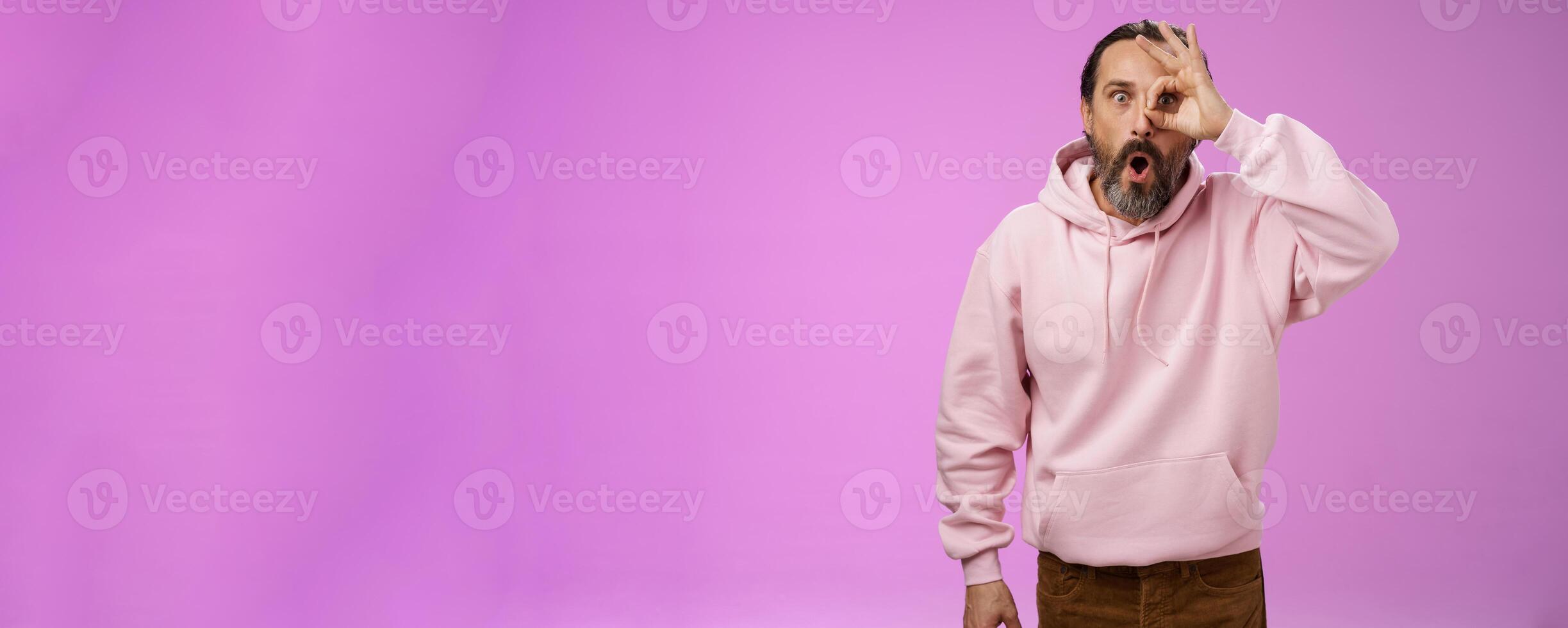 Impressed speechless handsome stylish old man bearded grey hair say wow drop jaw see incredible discount show okay ok excellent gesture eye look through amazed, standing pleased purple background photo