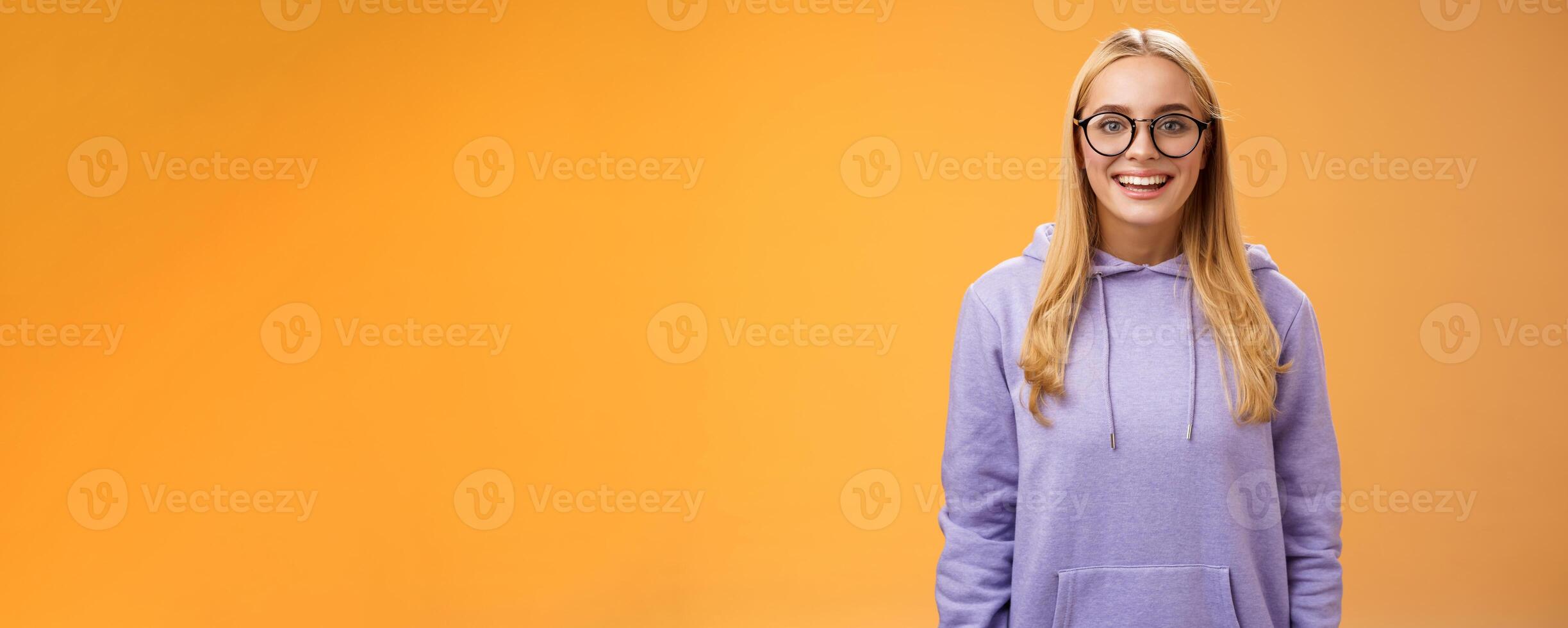 Charming female student geek smiling energized wanna participate university event grinning look excited wearing glasses purple hoodie standing amused orange background having fun photo