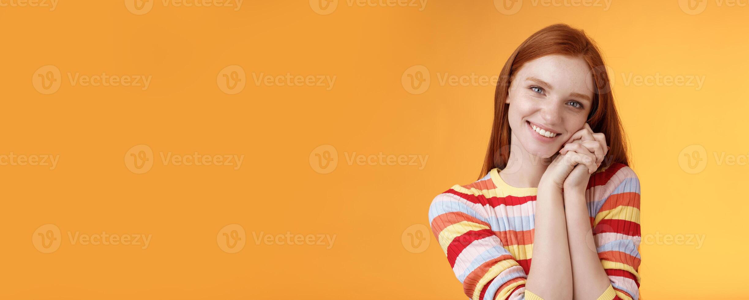 Romantic tender sensual attractive smiling redhead girlfriend melting heart feel warmth delighted lean palms grinning happily sweet gentle gift standing pleased orange background rejoicing thankful photo