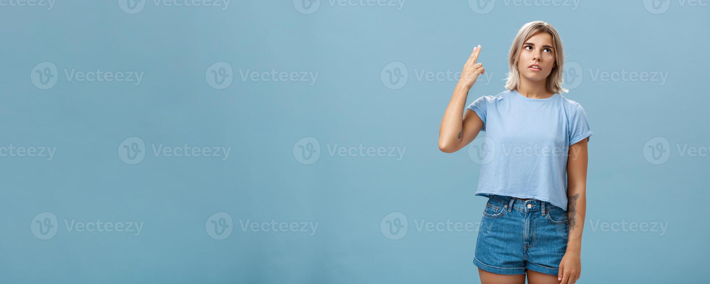 Stop teaching me how live my life. Portrait of irritated displeased attractive blonde female in denim shorts and casual t-shirt rolling eyelids from annoyance showing gun gesture as if blowing brains photo