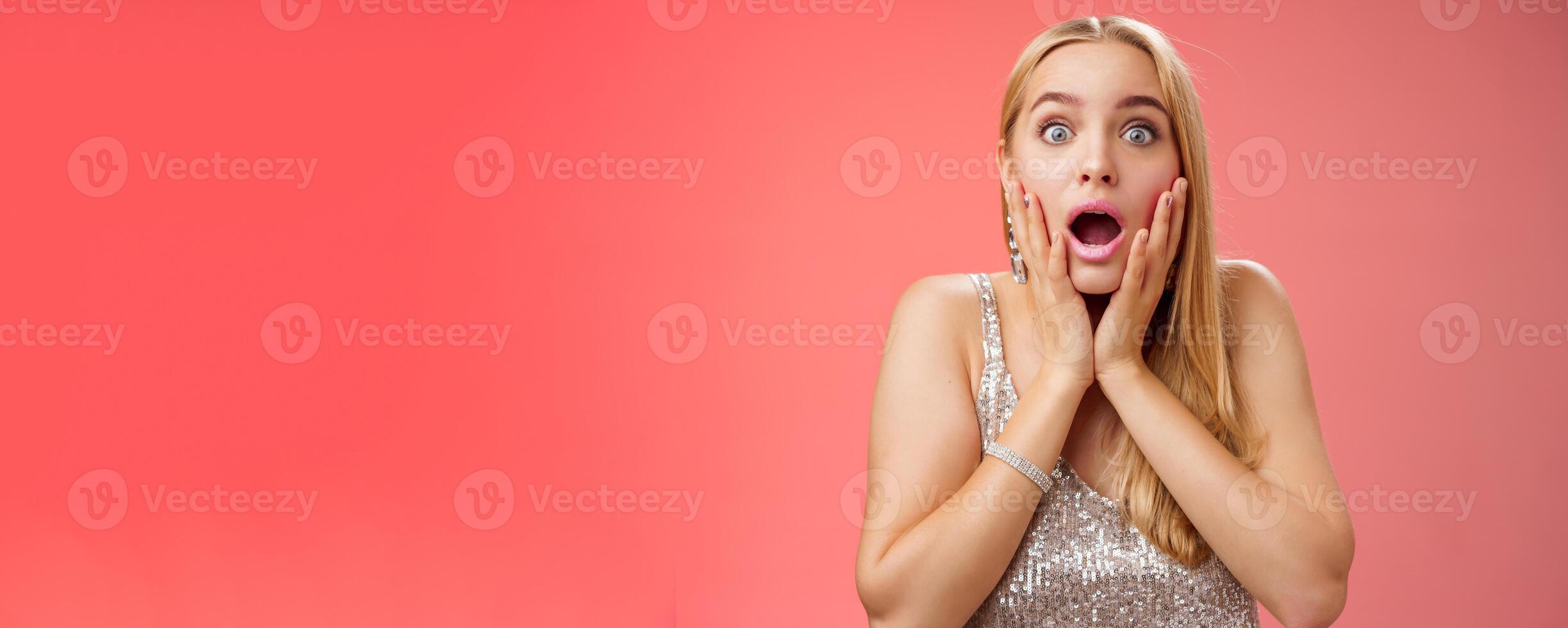Shocked speechless concerned young stunned woman gasping screaming worried drop jaw touch cheeks widen eyes surprised nervously staring camera troubled afraid, standing red background photo