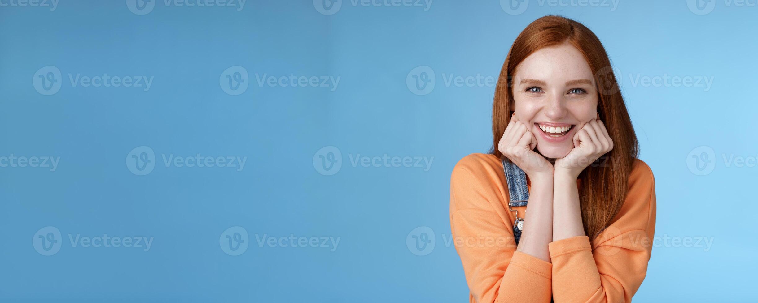 Enthusiastic sassy good-looking redhead caucasian girl lean head palms look amused intrigued listen interesting story pleased smiling laughing silly jokes standing blue background excited happy photo