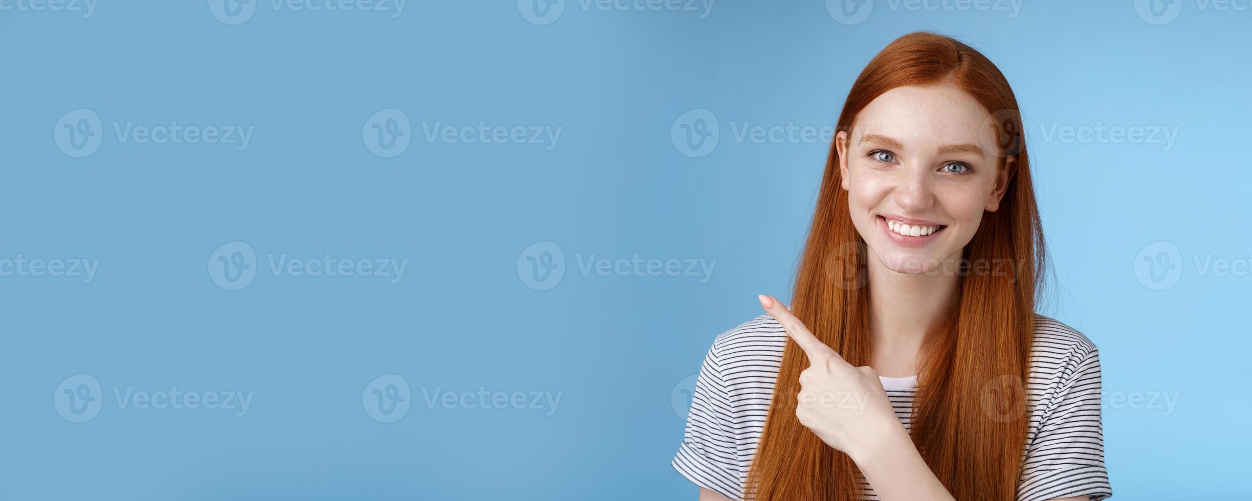 Close-up attractive gentle tender friendly-looking smiling redhead woman show place pointing upper left corner index finger grinning helpful giving choice help find store, standing blue background photo