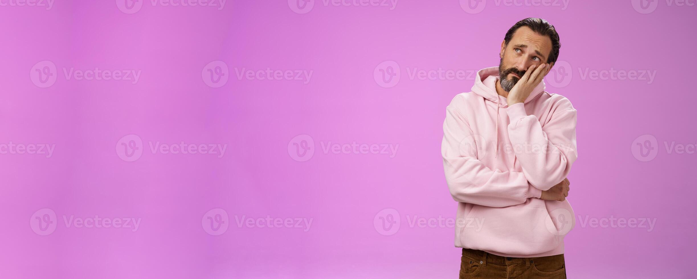 Sad gloomy bearded mature man lean head palm frowning look upper left corner thoughtful sorrow thinking bad times face hard problem standing upset disappointed down dumps, purple background photo