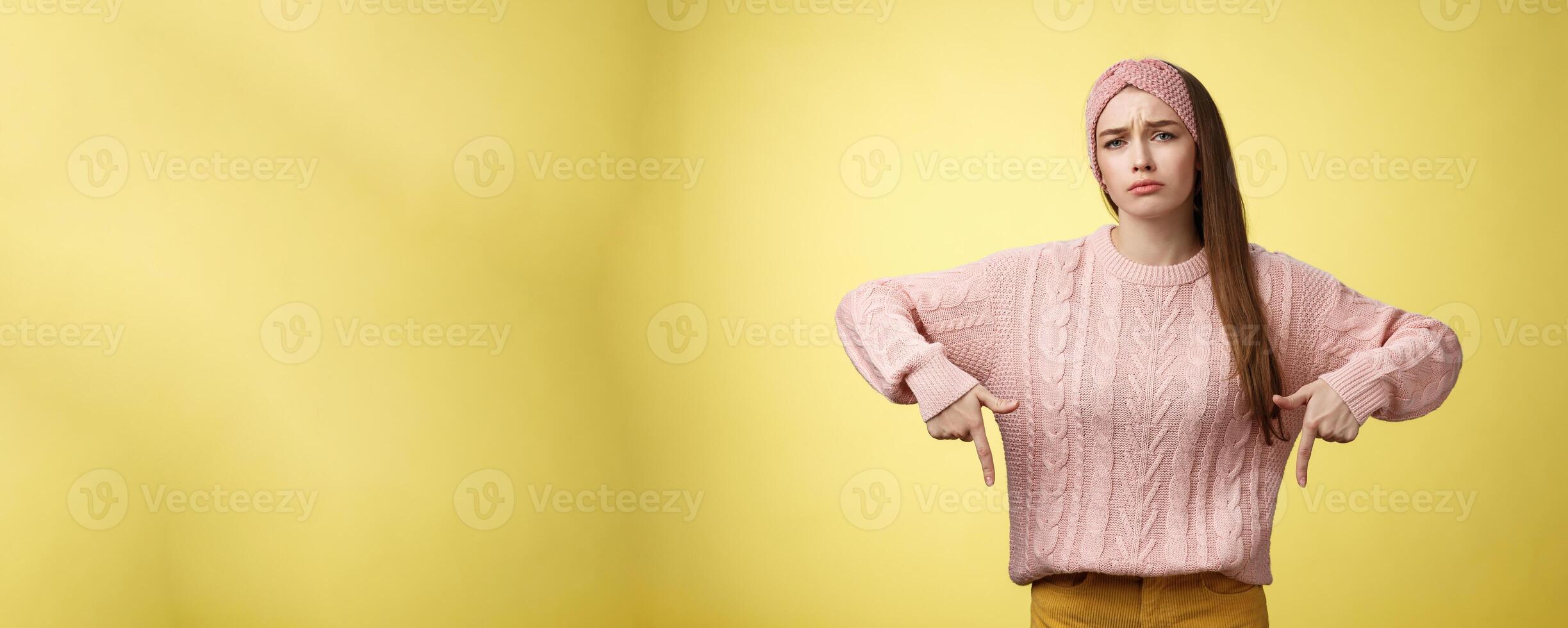 Why me, gosh. Gloomy upset complaining cute glamout young european girl in casual sweater, headband frowning, whining grimacing displeased pointing down, unhappy see lots work over yellow wall photo