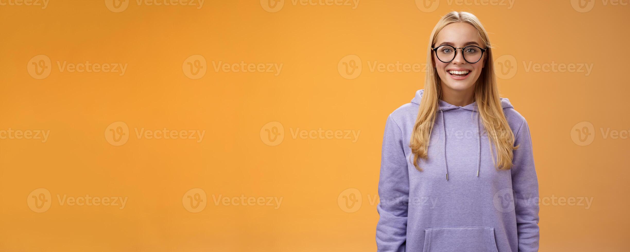 Charming female student geek smiling energized wanna participate university event grinning look excited wearing glasses purple hoodie standing amused orange background having fun photo