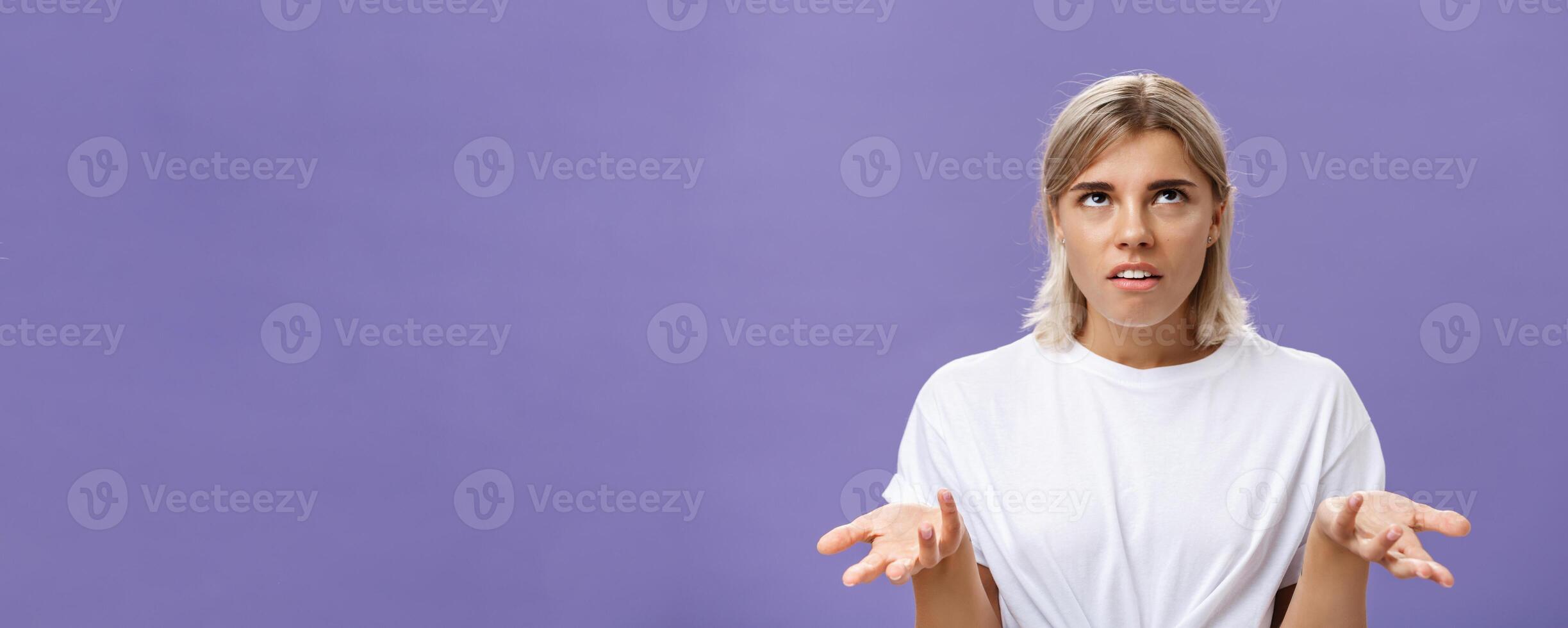 Nah I have no idea. Portrait of irritated bothered good-looking european woman with fair hair rolling eyes up with disappointed expression shrugging with hands raised in clueless gesture photo