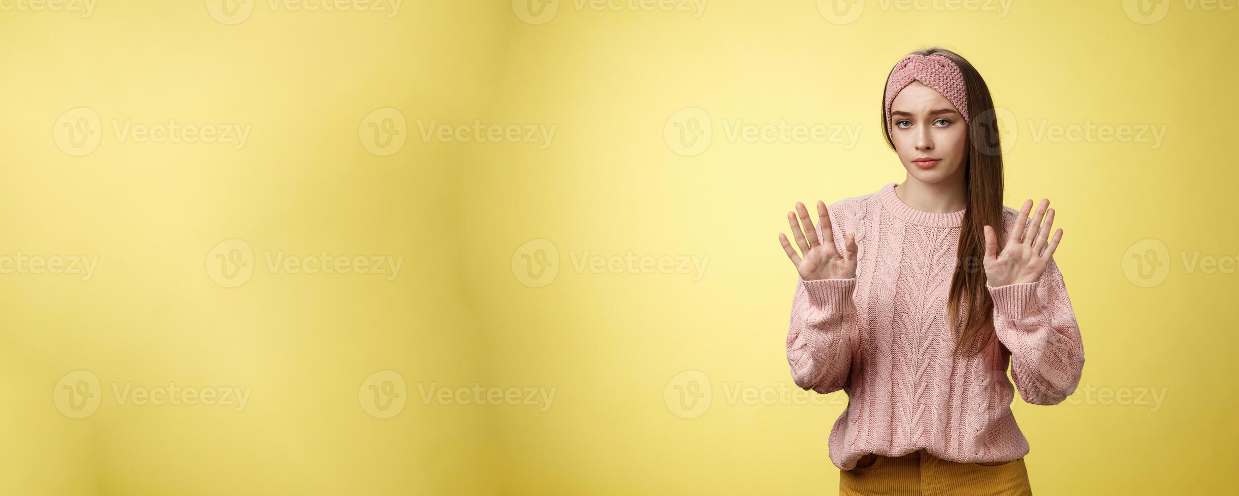 No thanks. Cute unamused picky young girl in knitted sweater, headband showing hold on, slow down, refusal gesture raising palms in rejection being reluctant unimpressed and indifferent to proposal photo