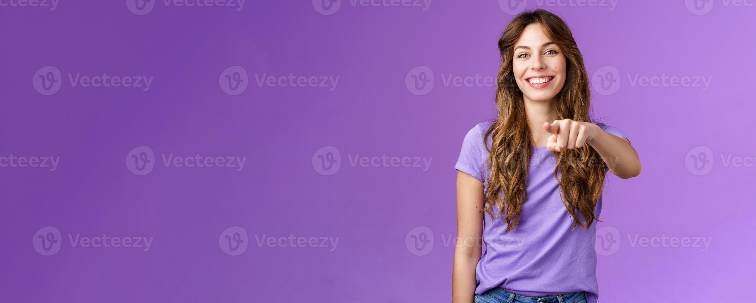 Cheerful girl pointing you. Attractive friendly happy smiling curly-haired female deciding who pick indicating finger camera grinning joyful inviting coworker her team stand purple background photo
