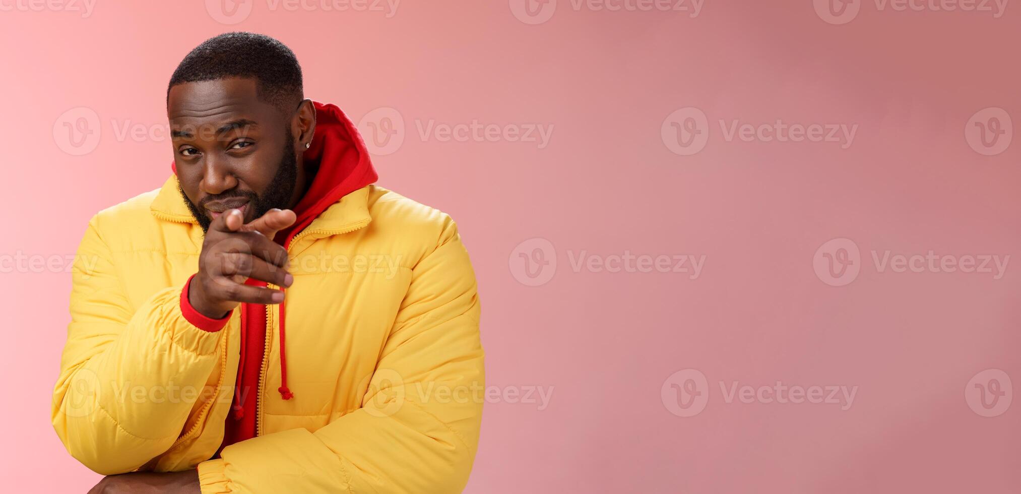 Guy suspecting you pointing camera index finger squinting disbelief unsure, standing pink background asking question look doubtful hesitant, express distrust wear yellow jacket red hoodie photo