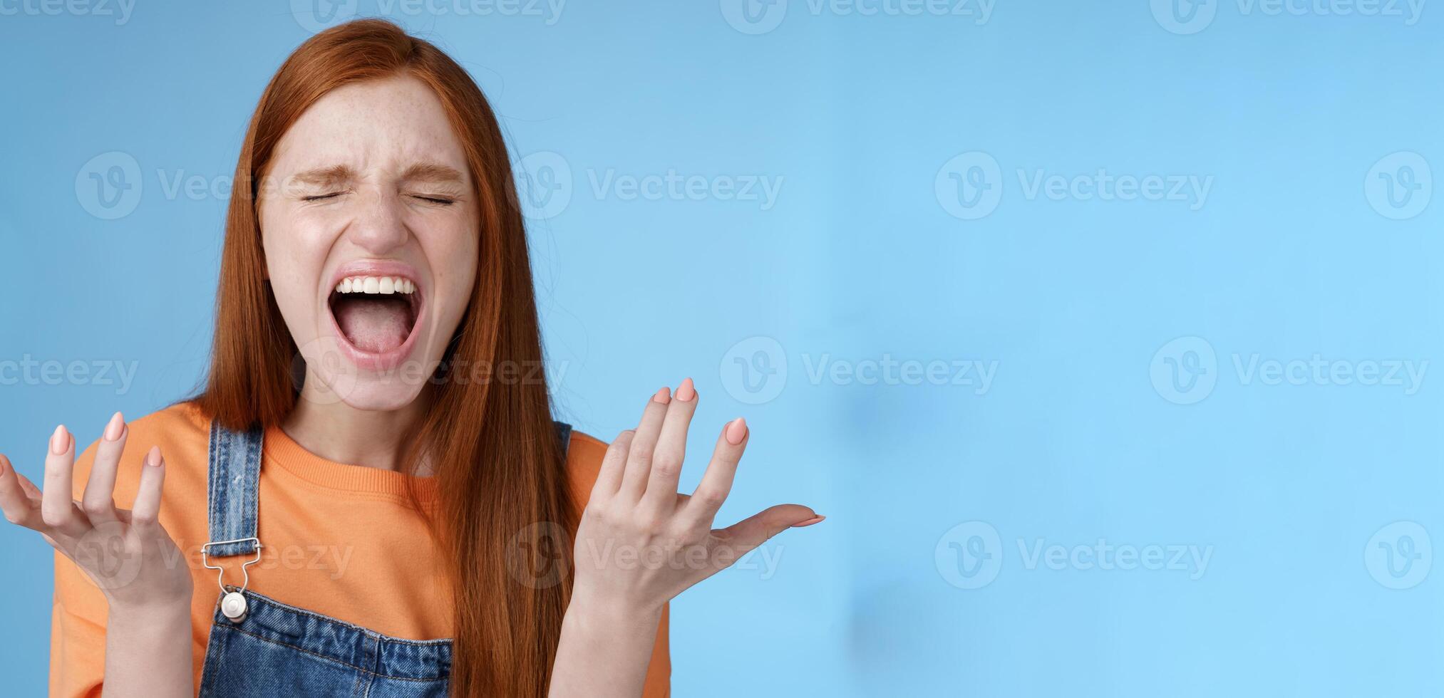 Pissed outraged moody redhead girl shouting complaining angry standing bothered screaming out loud close eyes yelling loudly raising hands sideways dismay full disbelief feel cheated painful betrayal photo