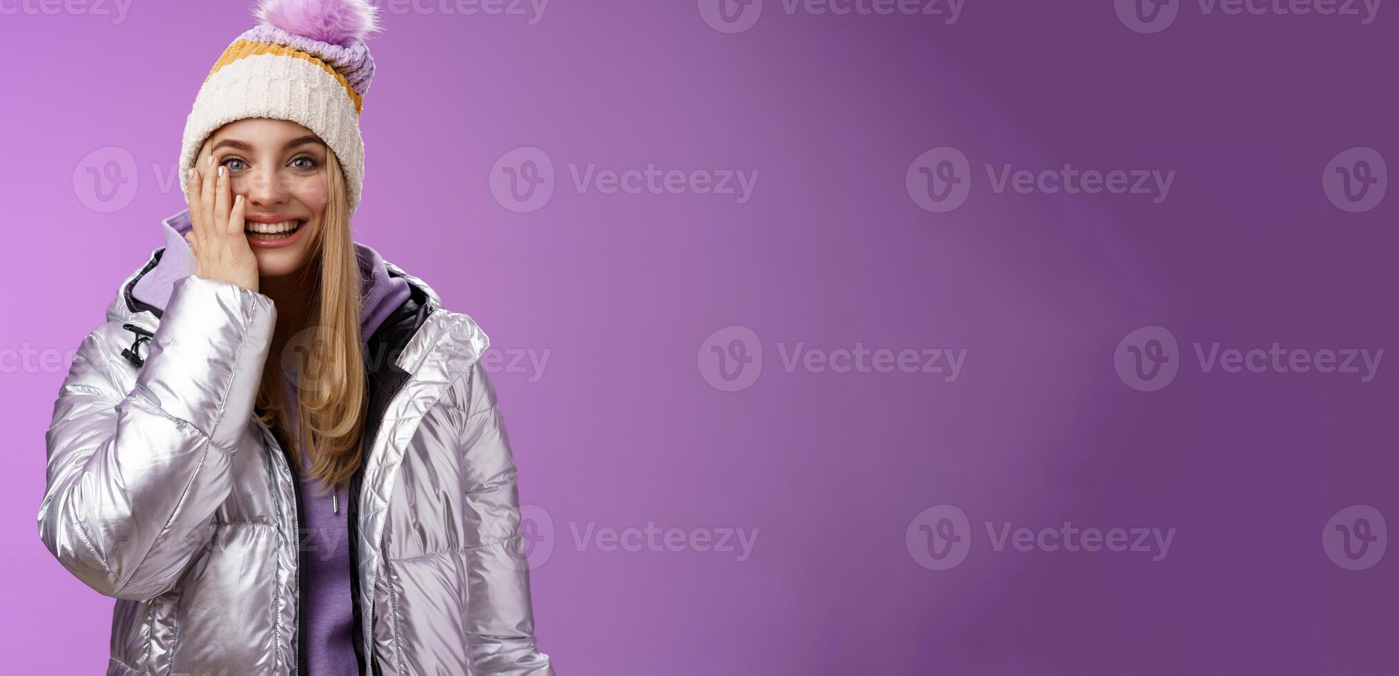 Delighted amused tender blond girlfriend fool around look playful playing snowballs touch cheek astonished feel dream come true enjoying vacation winter holidays boyfriend, standing purple background photo