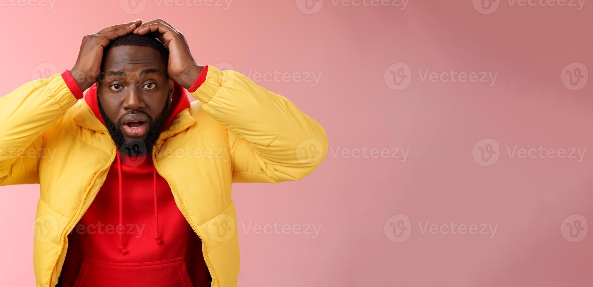 Shocked stupefied young african-american bearded man grab head drop jaw gasping confused frustrated looking upset troubled have problems standing stunned concerned pink background photo