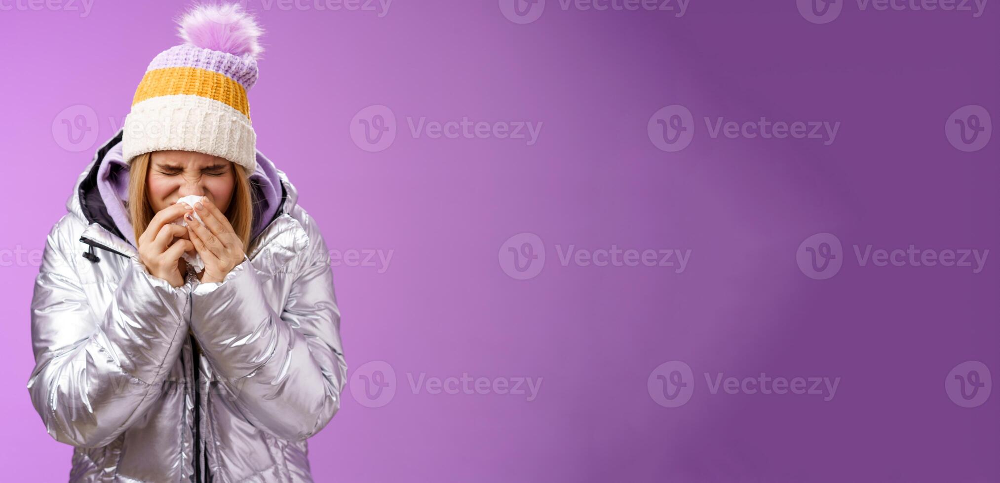 Girl runny nose sneeze tissue press napkin face got ill feeling unwell sick heading hospital standing purple background bending wearing silver stylish jacket winter hat, crying sobbing photo