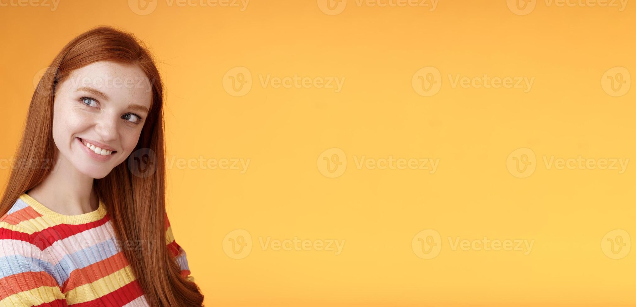 Silly flirty good-looking redhead girl making first move checking out guy standing profile turning left smiling intrigued glancing aside coquettish flirting seducing sassy, orange background photo