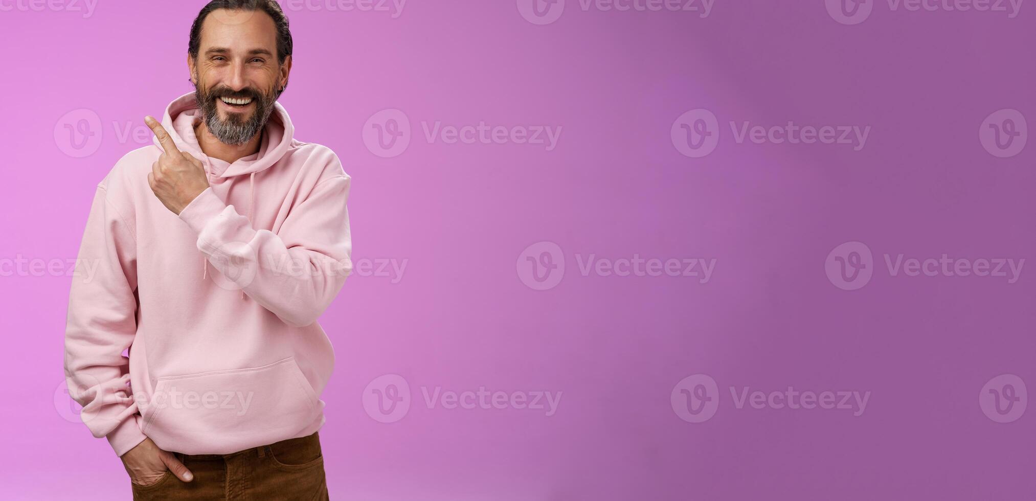 Charming friendly happy mature man 50s bearded grey hair laughing happily pointing upper left corner behind showing proudly family members standing purple background having fun stay positive photo