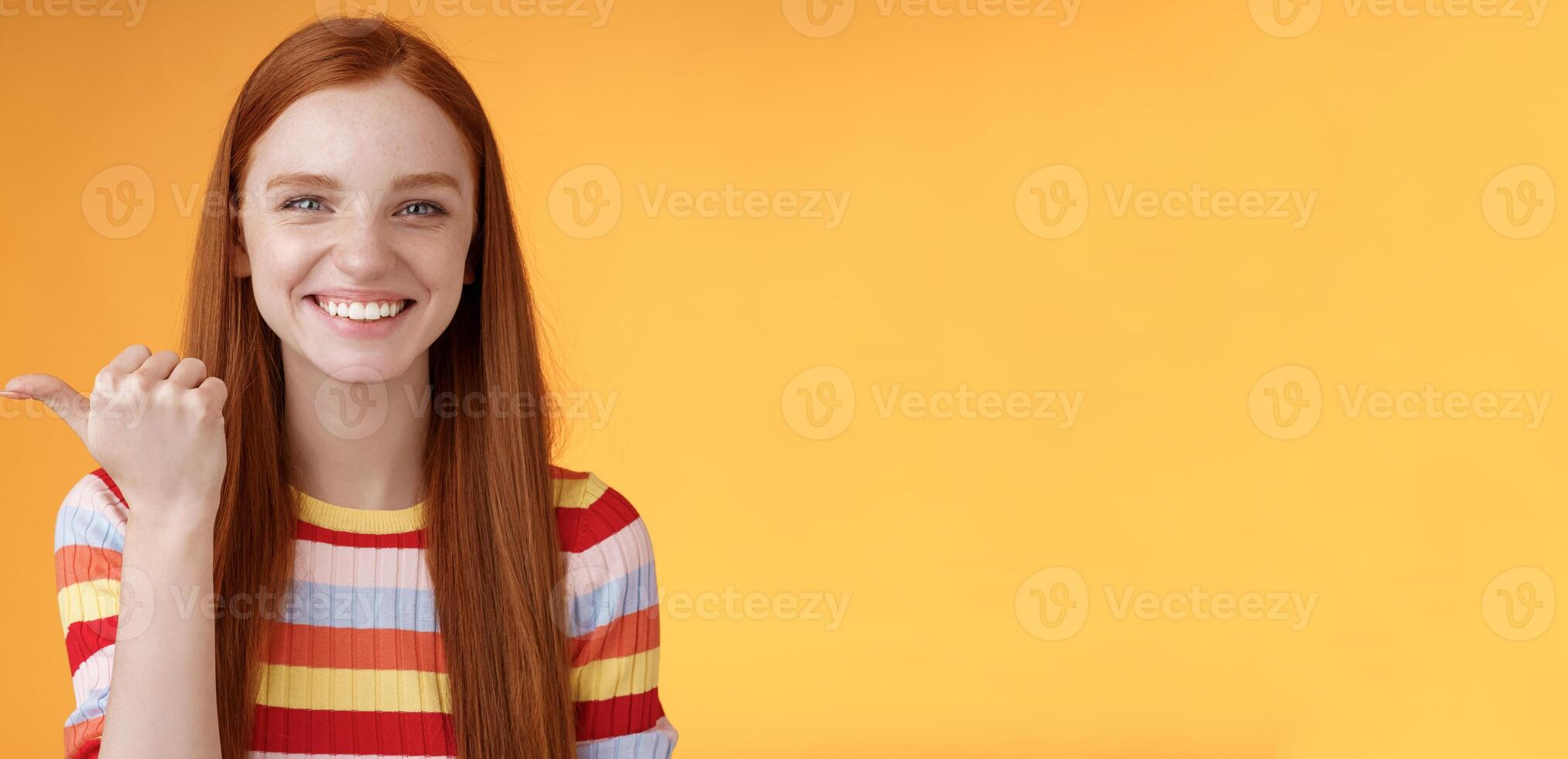 Girl pointing left cool person can help smiling delighted look friendly camera discuss interesting project introduce friend during conversation standing happy grinning orange background photo