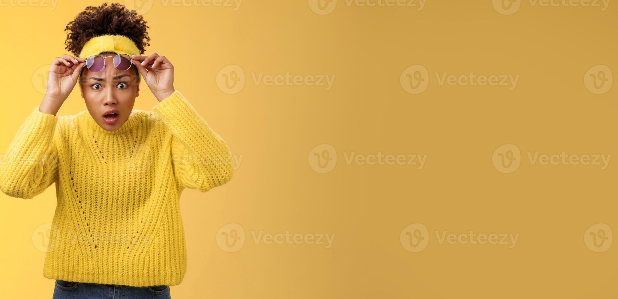 What heck. Shocked stunned confused african-american stylish modern girl in sweater headband take-off sunglasses widen eyes surprise speechless gasping look questioned freak-out, yellow background photo