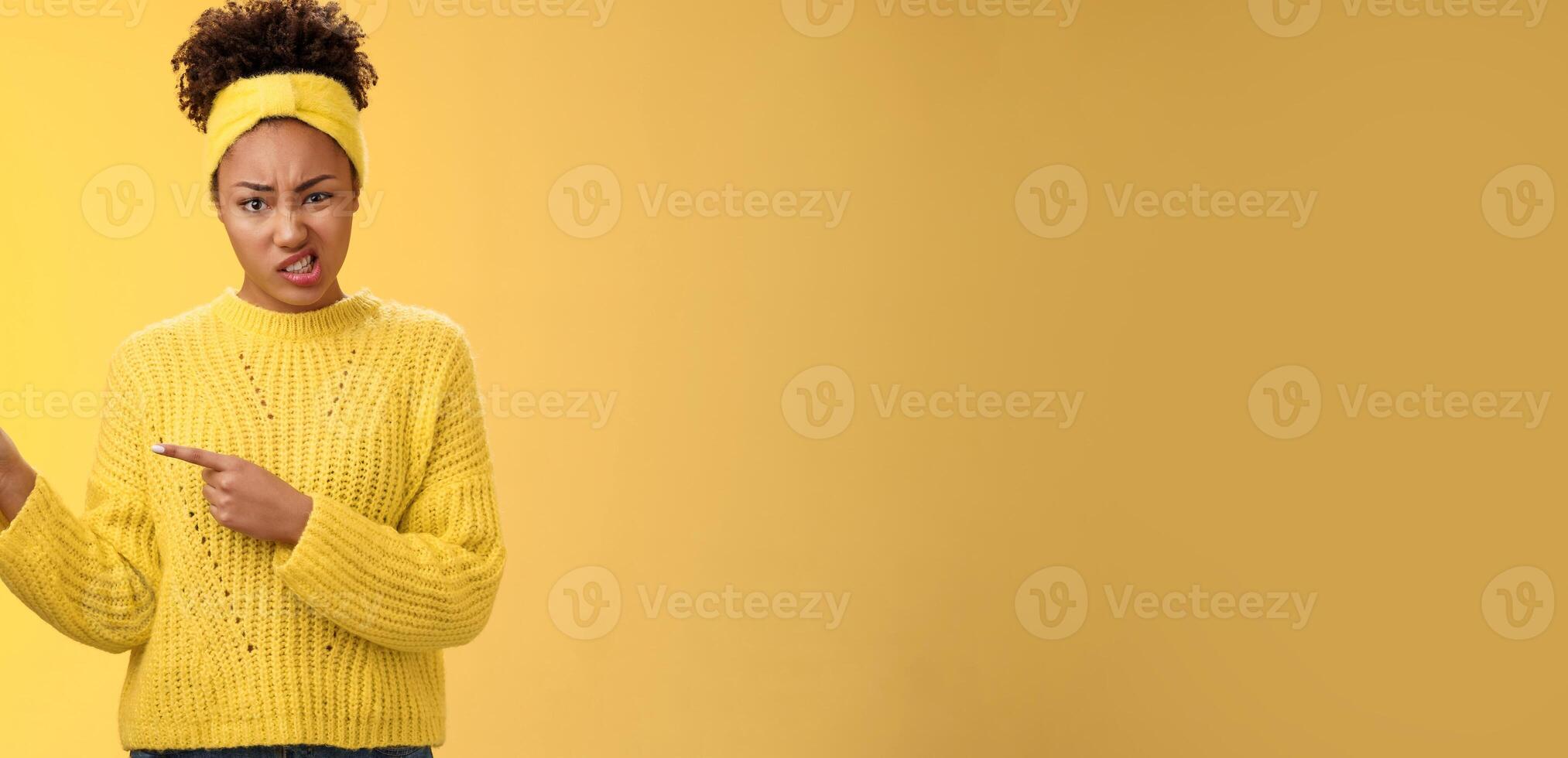 Attractive peeky glamour african-american girlfriend express dislike doubt frowning cringing aversion disappointed pointing left high hopes ruined, look disdain feel dismay yellow background photo