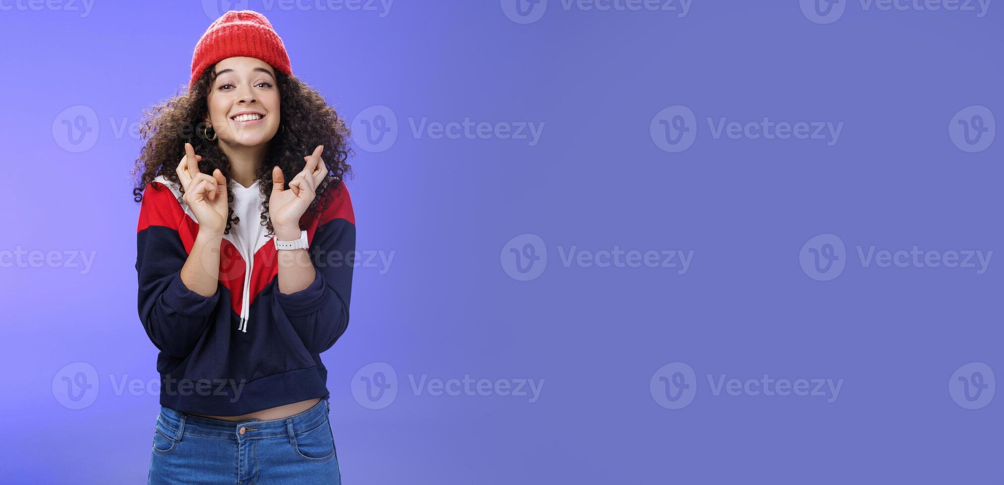 Dreamy optimistic woman praying friend will win standing supportive and excited smiling hopeful crossing fingers god good luck, waiting for miracle and dream come true posing against blue background photo