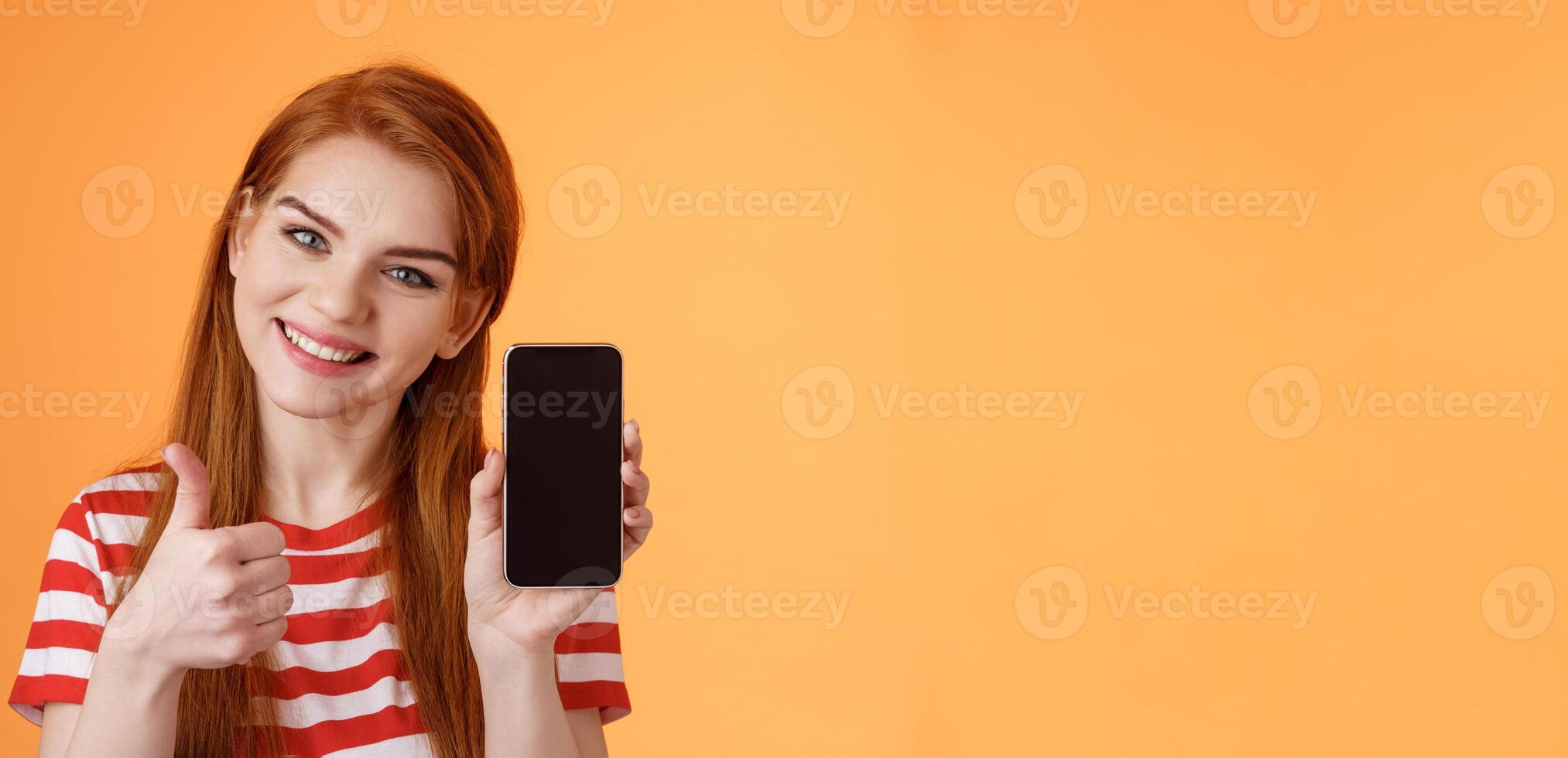 Best smartphone app guarantee. Assertive lovely friendly-looking redhead woman recommend cellphone application, introduce online store website, like give thumb-up approval, stand orange background photo