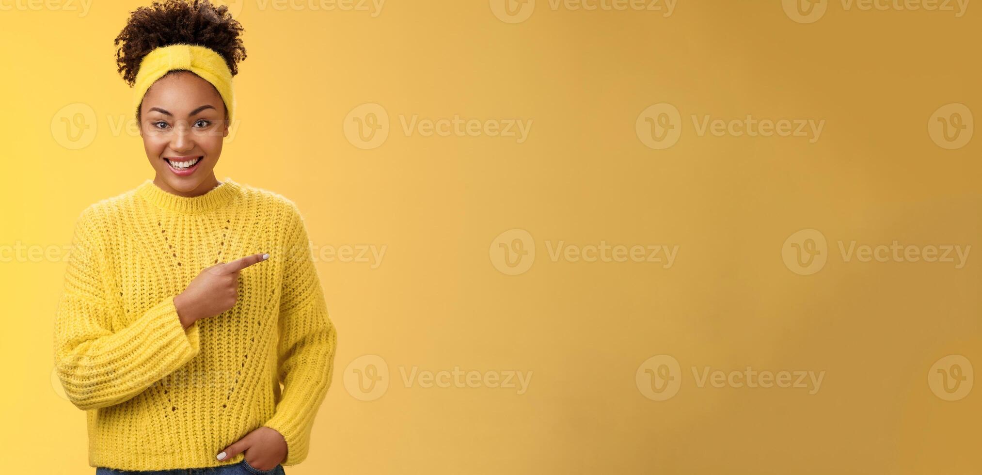 Friendly ougoing relaxed african-american woman casually pointing right during conversation discussing recent new cafe open awesome discounts promos standing happily yellow background photo