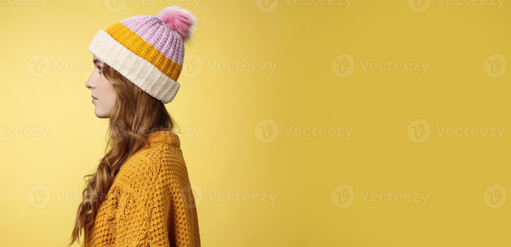 Profile shot attractive female curly hairstyle wearing hat knitted sweater standing queue order hot warm drink look left normal casual expression, posing yellow background studio photo