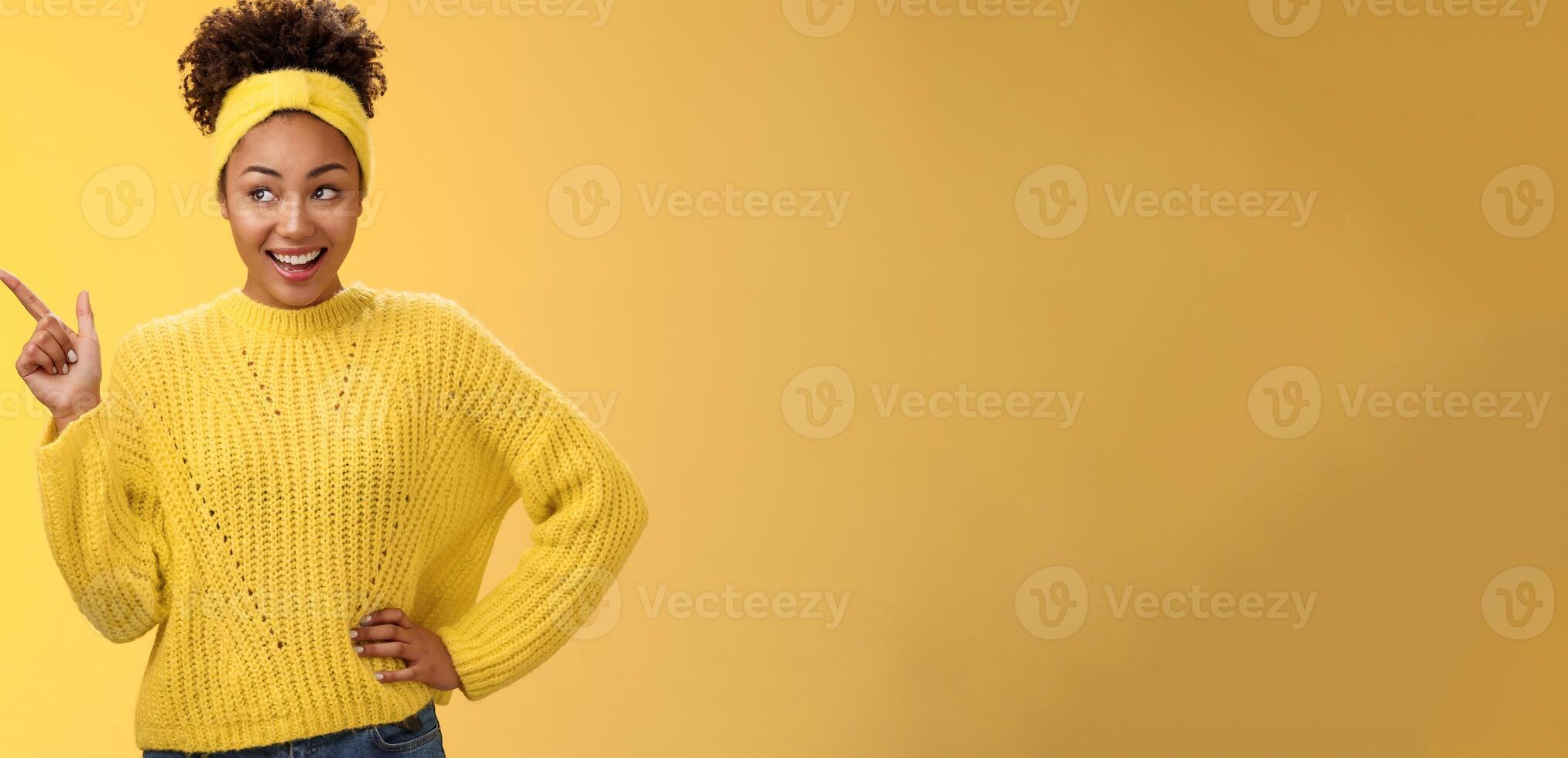 Charming tender young easy-going millennial stylish girl in sweater hold hand waist confident pointing looking impressed upper left corner smiling broadly ineterested, curiously discussing product photo