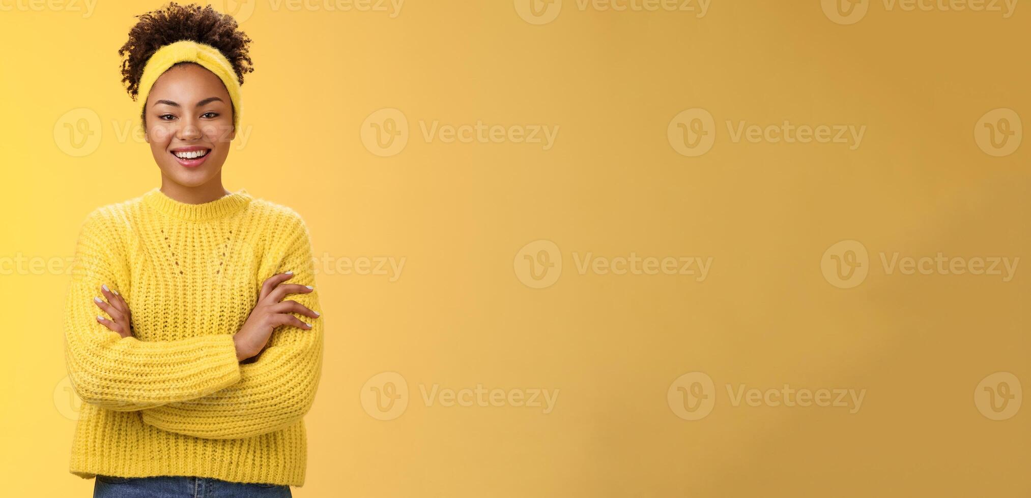 Serious powerful good-looking smiling african-american female femenist blogger cross hands chest confident pose grinning delighted enjoying watching working process, standing yellow background photo