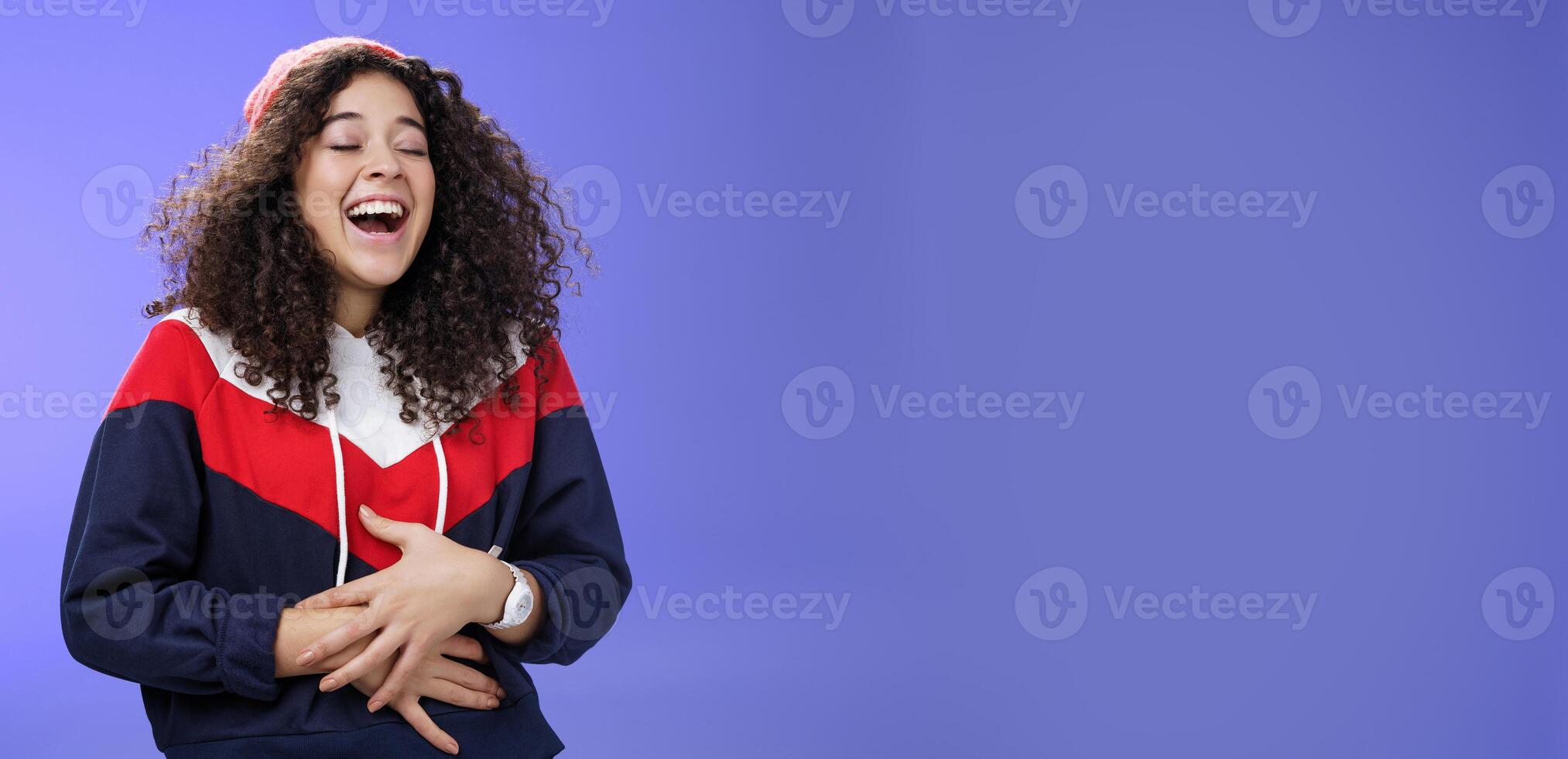 Girl hearing hilarious funny joke, making prank over friend laughing out loud feeling pain in belly as giggling too much holding hands on stomach close eyes and tilting back from joy and amusement photo