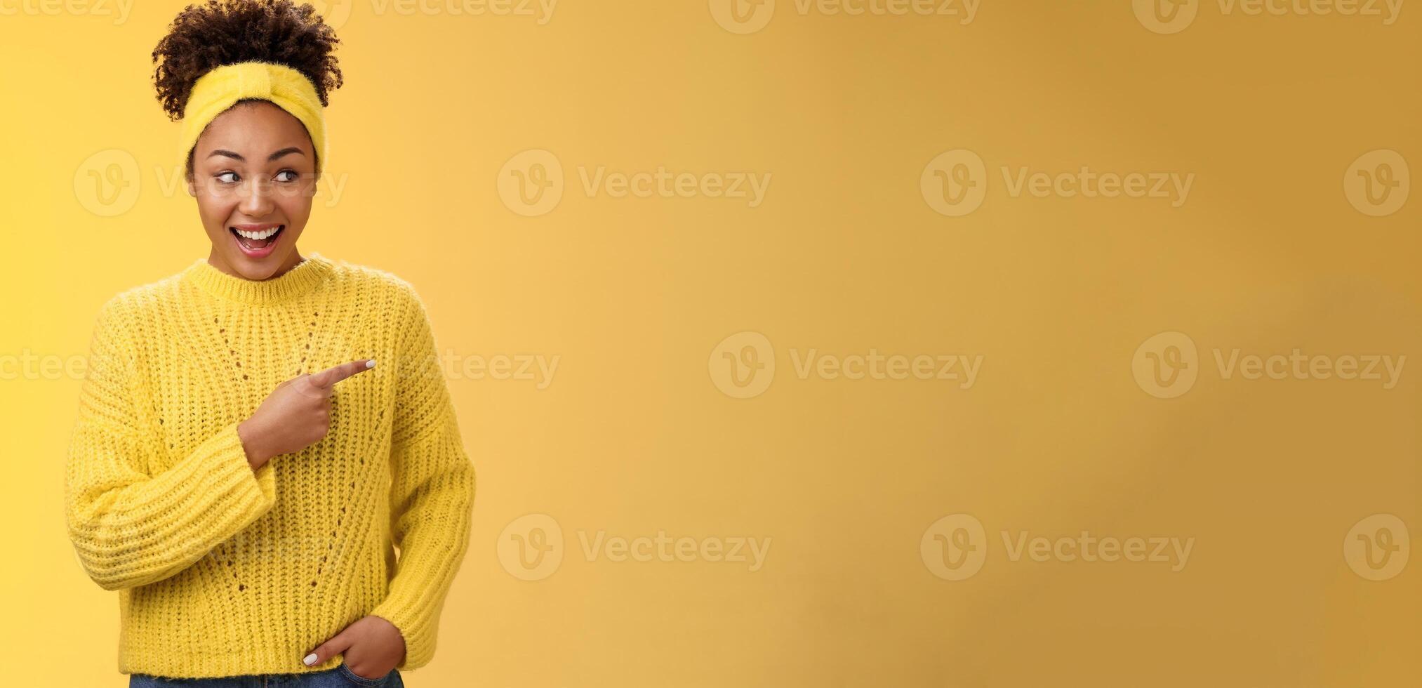 Astonished cute feminine modern african-american woman gossiping silly laughing drop jaw laughing surprised pointing right discuss during conversation interesting rumour place, yellow background photo