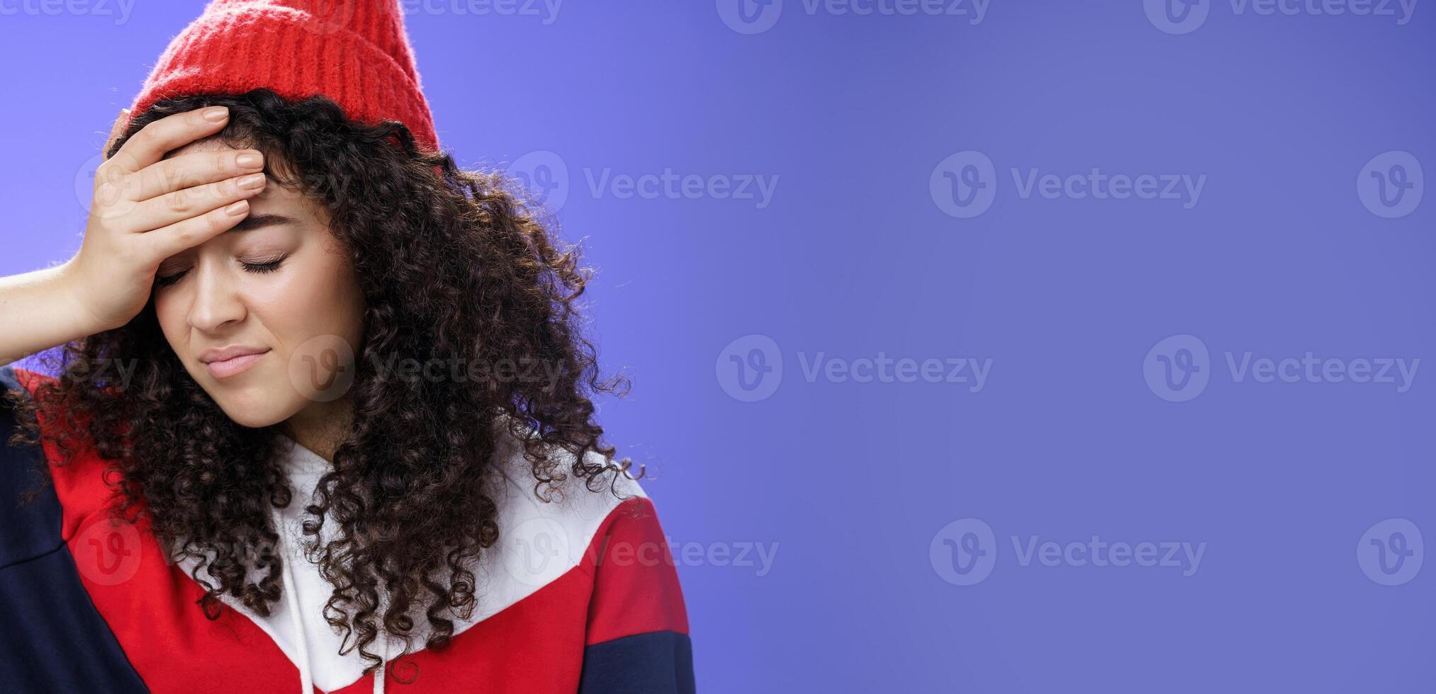 Oh god why me. Portrait of pissed and irritated fed up cute girl with curly hair looking down with regret and disappointed making facepalm gesture from annoyance being bothered by stupid question photo