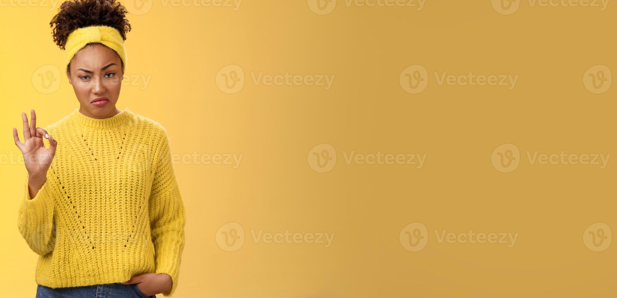 Well not bad. Portrait serious-looking confident arrogant young african-american woman agree effort good show okay ok normal gesture smug approval, standing yellow background impressed photo