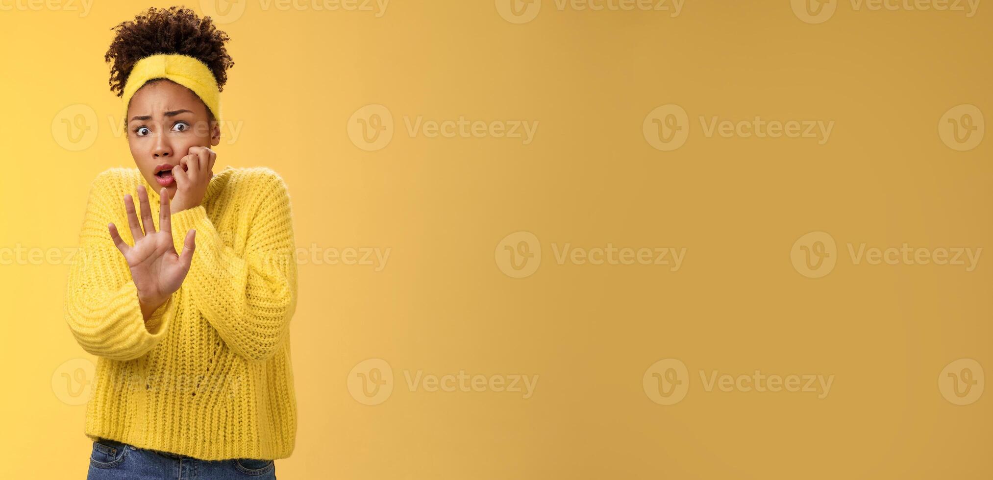 Terrified female victim scared abuse look afraid frightened extend arm begging not hurt come close widen eyes biting fingernails gasping shocked standing stunned frightened, horrified yellow wall photo