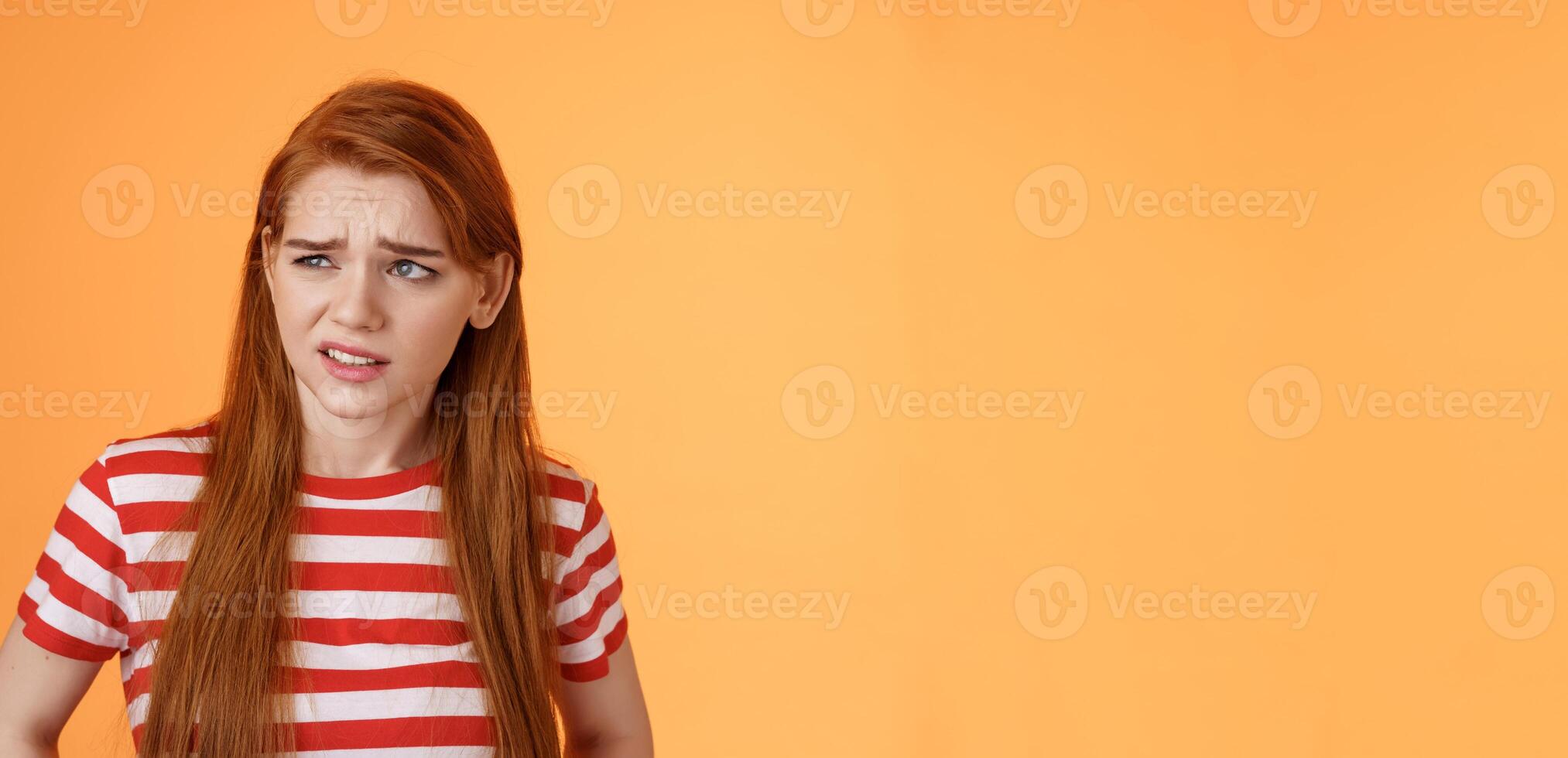 Close-up unsure redhead teenager frowning uncertain, having doubts, look perplexed left side copy space, hesitating, cringe dislike and disappointment, stare frustrated, uneasy decision photo