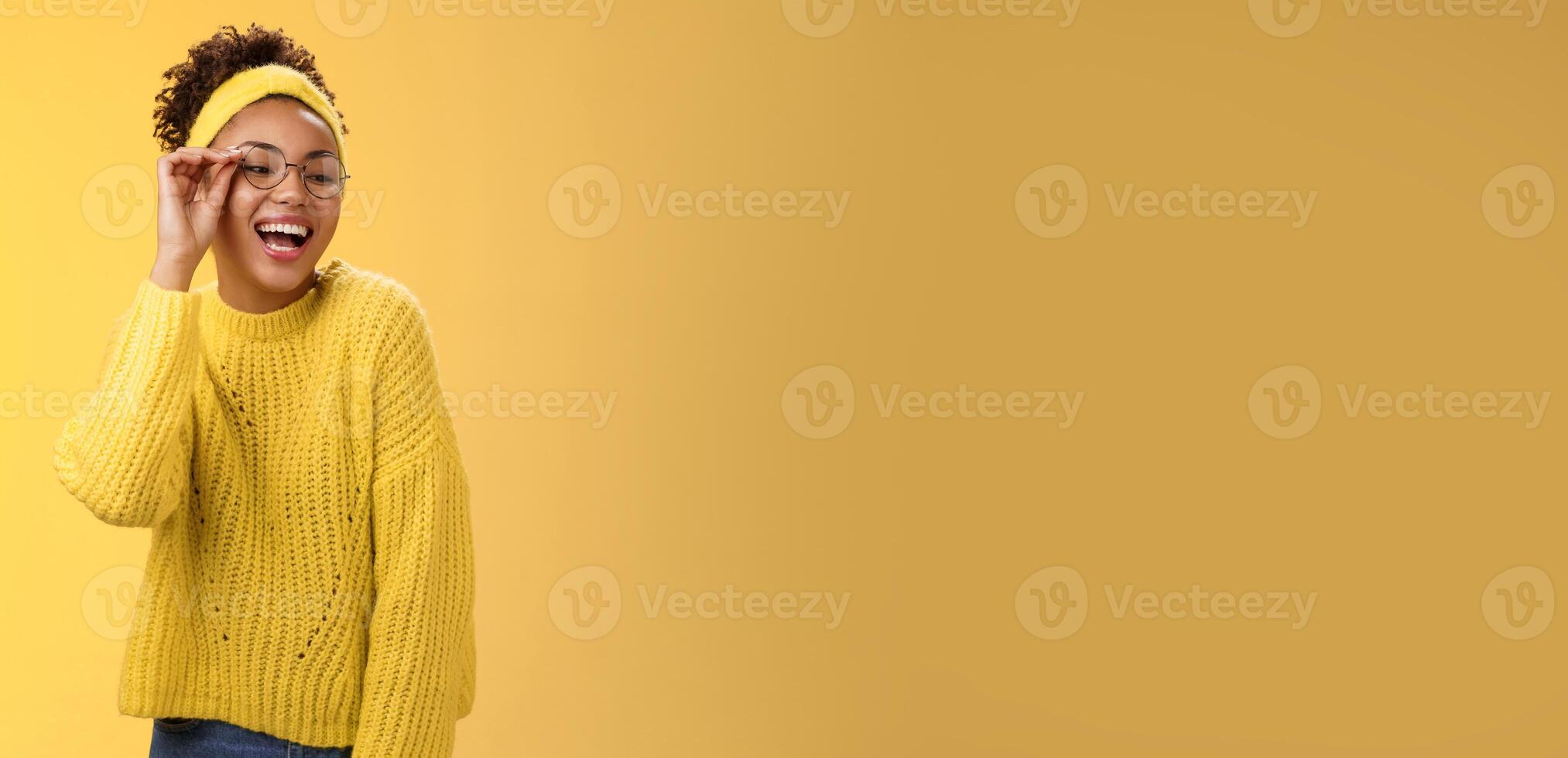 Charismatic stylish confident beautiful african-american joyful teenage girl touching glasses nose laughing broadly look down right corner grinning have fun joking enjoying, yellow background photo