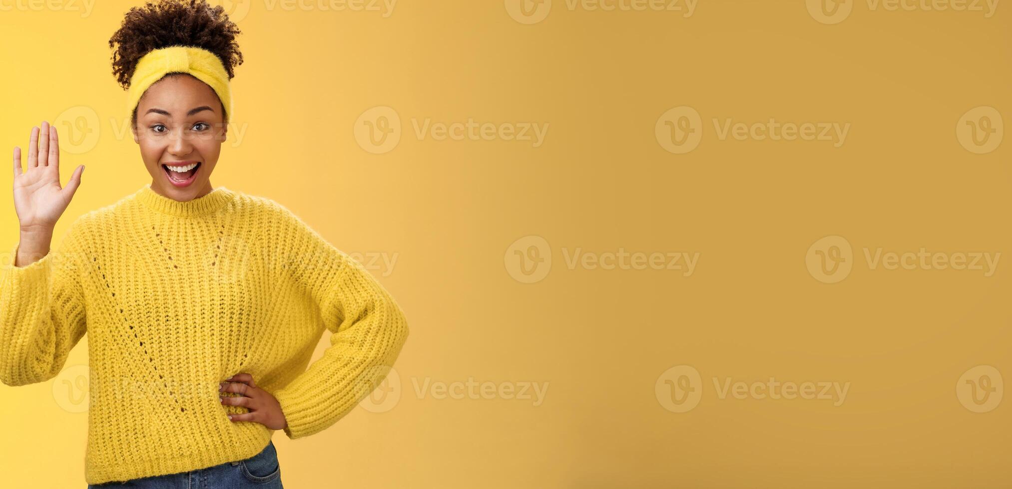 Girl raising hand gladly willing participate be candidate say hi hello waving palm greeting gesture smiling broadly feel happy gladly welcoming friends inviting party near door yellow background photo