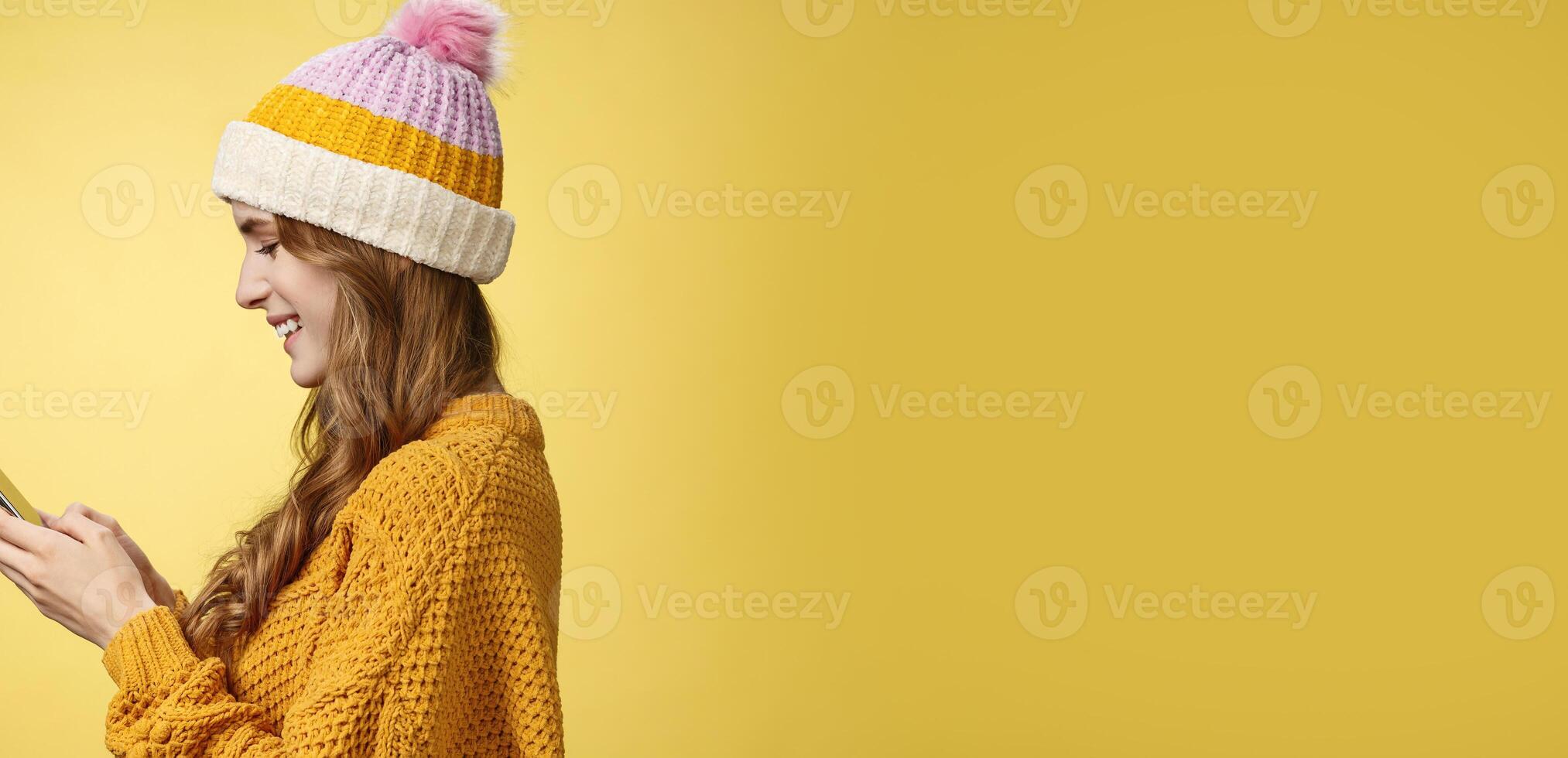 Profile shot charming outgoing relaxed young modern millennial girl texting smiling broadly holding smartphone looking display amused editing pic post online, blogger messaging followers photo