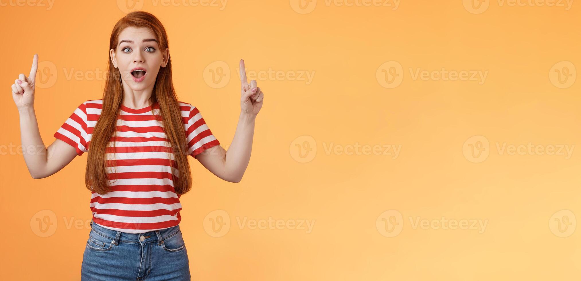Surprised cute girl 20s long red hair lovely ears, inspired awesome interesting lecture showing you copy space up promo, open mouth amused, fascinated stare camera, explain news photo