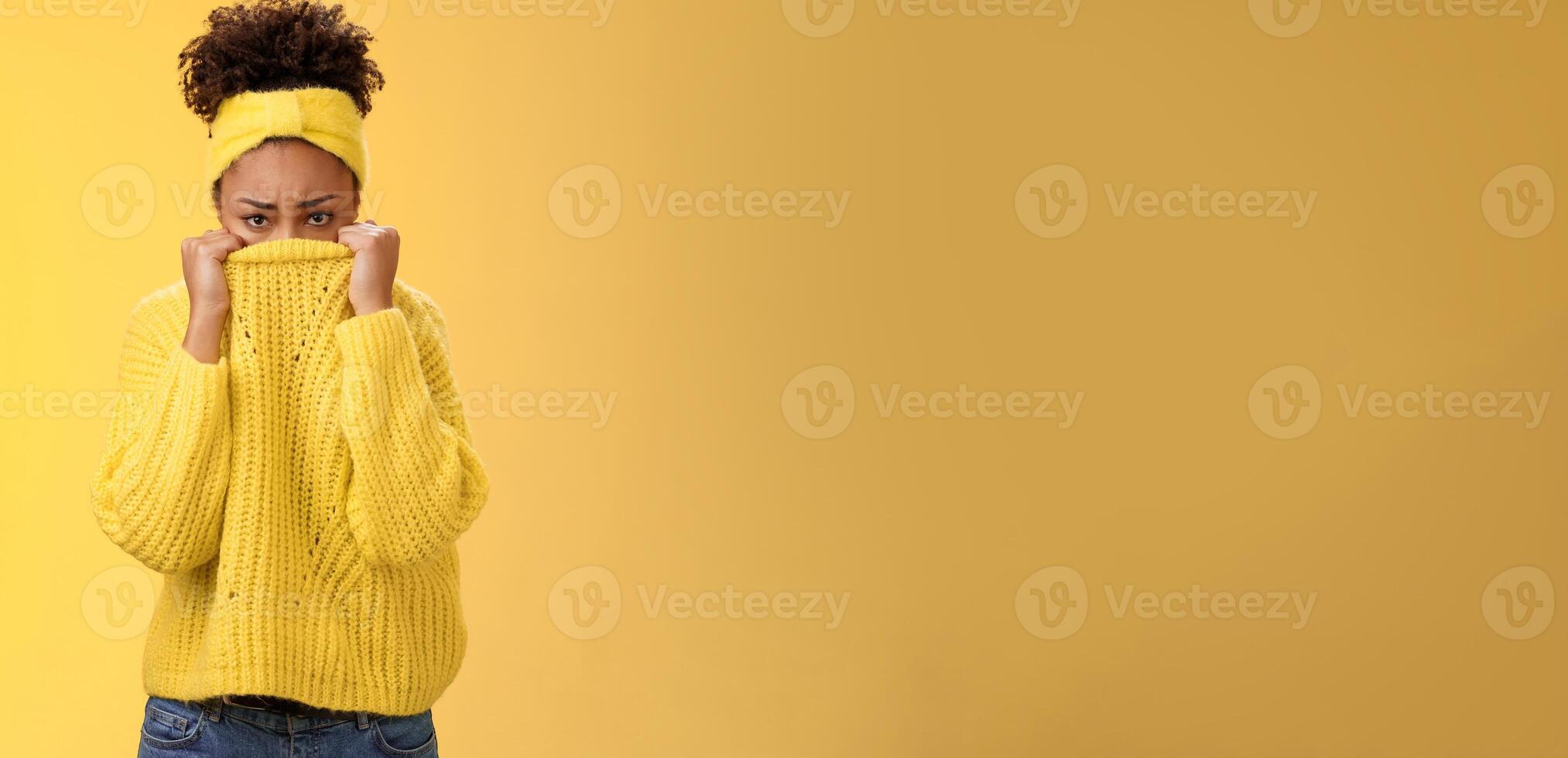 Cute upset scared timid insecure african-american offended girl hiding face pulling sweater collar nose frowning pouting look sorrow insulted afraid watching scary horror movie alone, need support photo