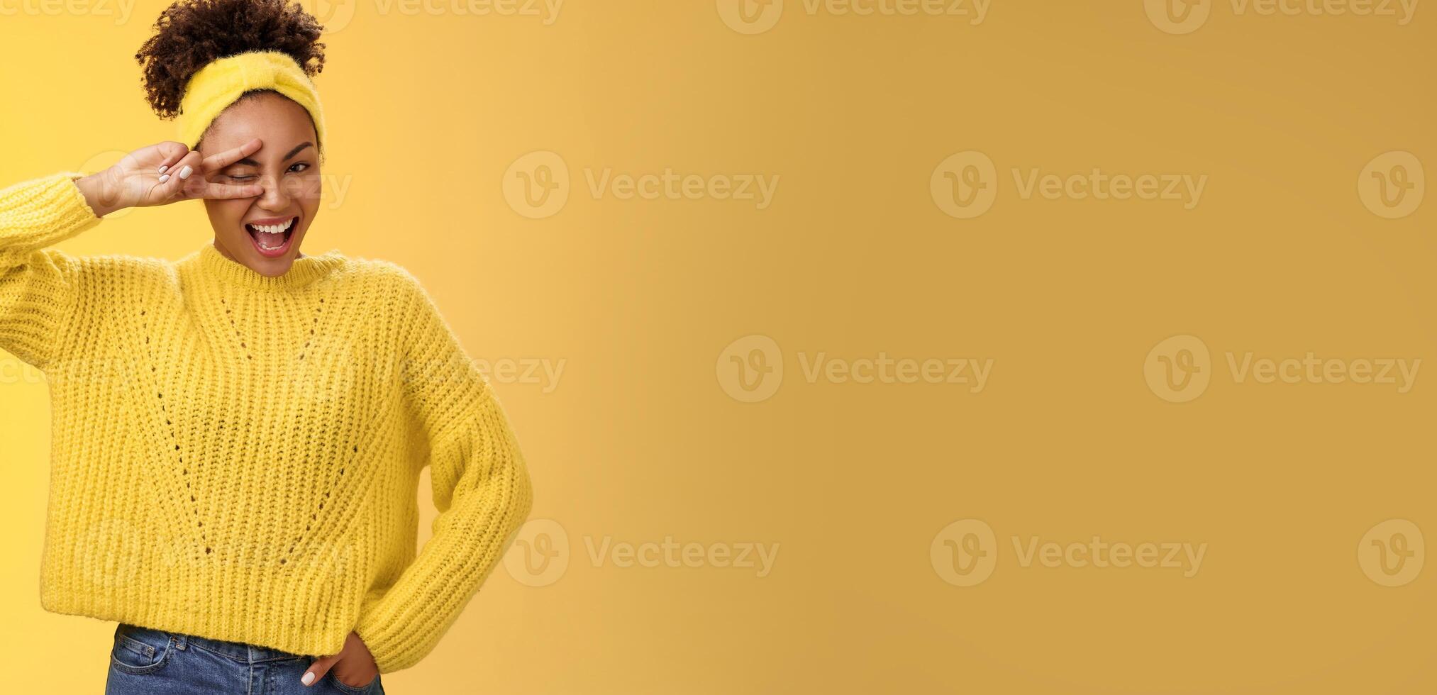 Friendly self-assured energetic african-american smiling healthy girl winking positive attitude grinning cheerful show peace victory lucky gesture hold hand waist confident, yellow background photo