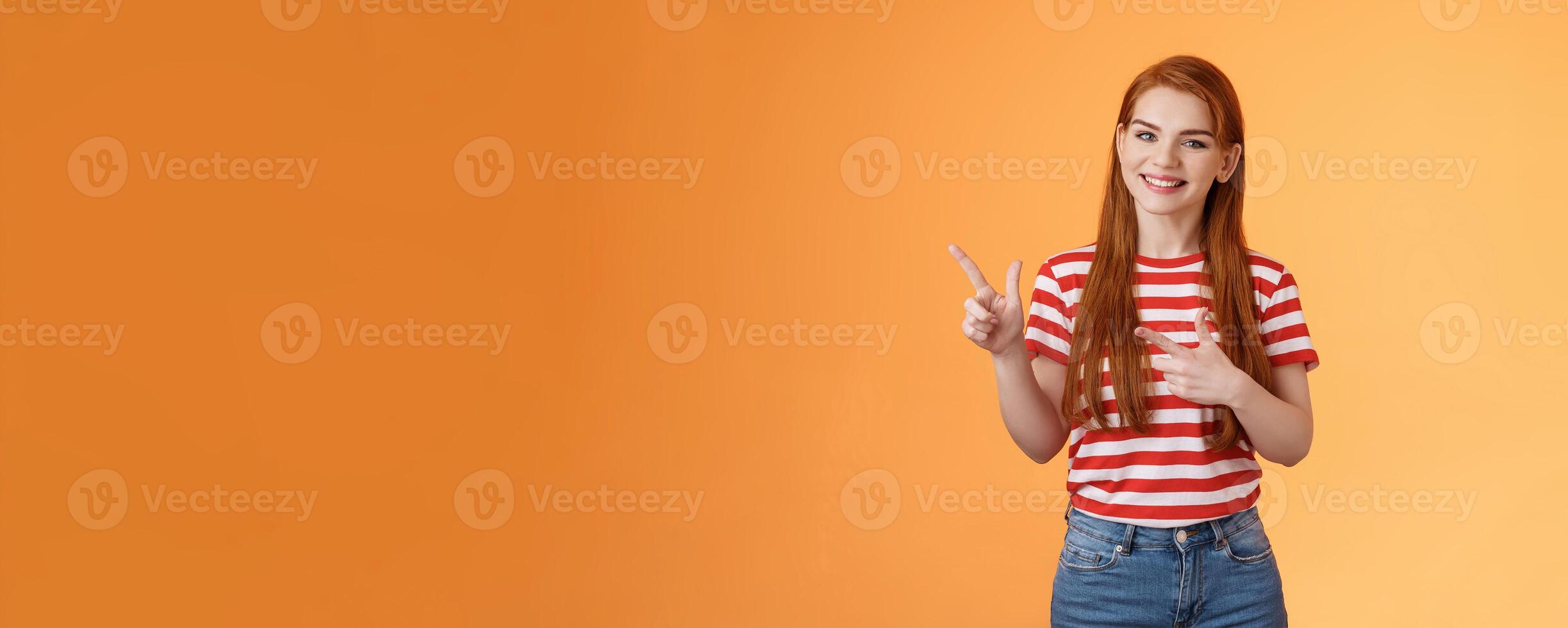 Cheerful pleasant female professional assistant showing customers office, pointing left smiling cheerful, gladly help out pick product, introduce new promos copy space, stand orange background photo