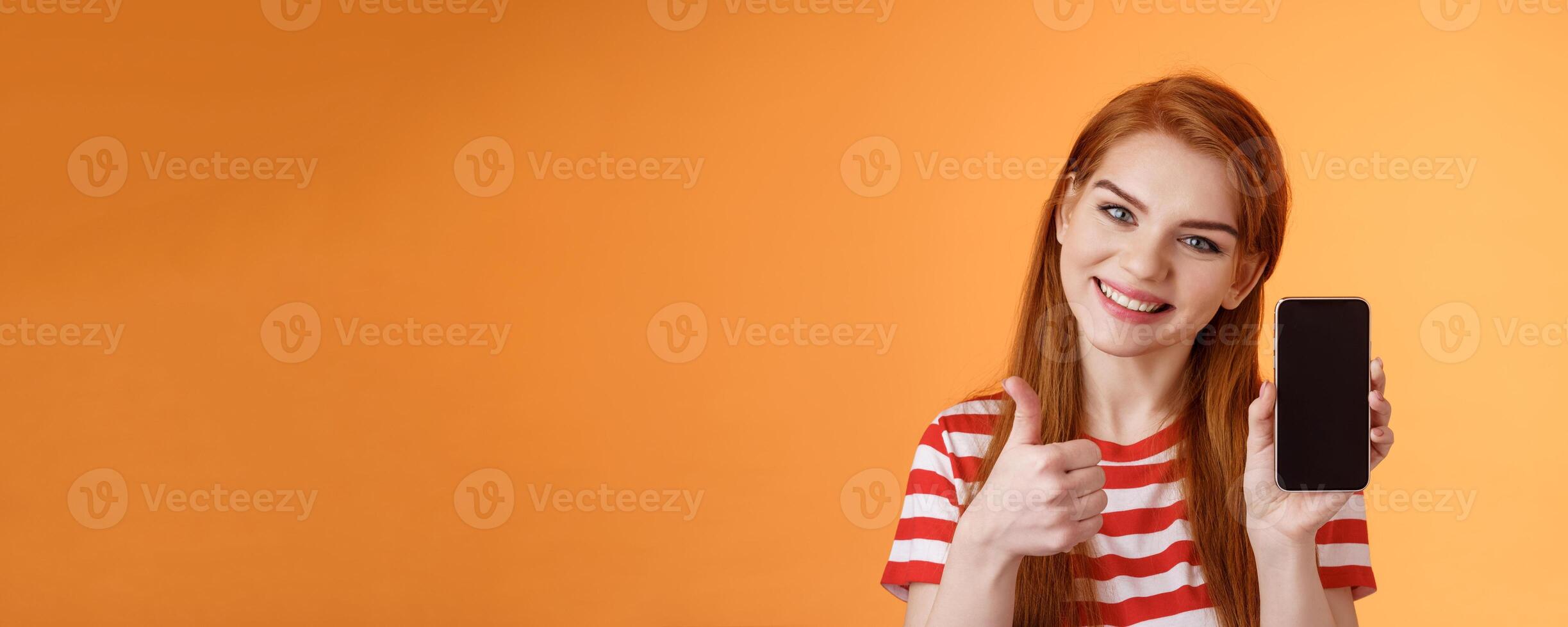 Best smartphone app guarantee. Assertive lovely friendly-looking redhead woman recommend cellphone application, introduce online store website, like give thumb-up approval, stand orange background photo
