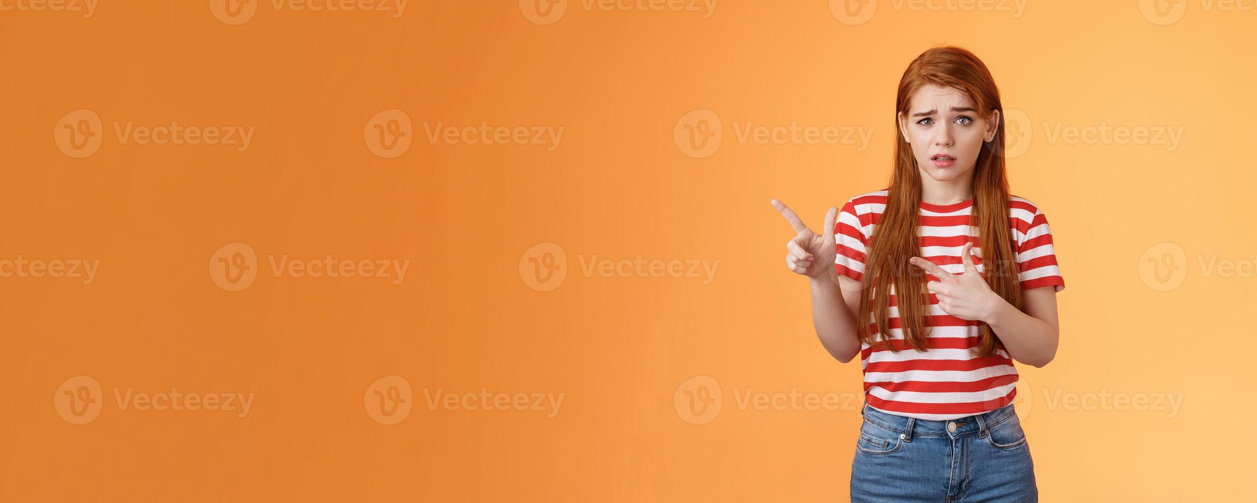 Insecure questioned frustrated cute redhead girl feel nervous unsure about suspicious offer frowning, grimacing doubtful and hesitant, pointing left look camera puzzled, asking question photo